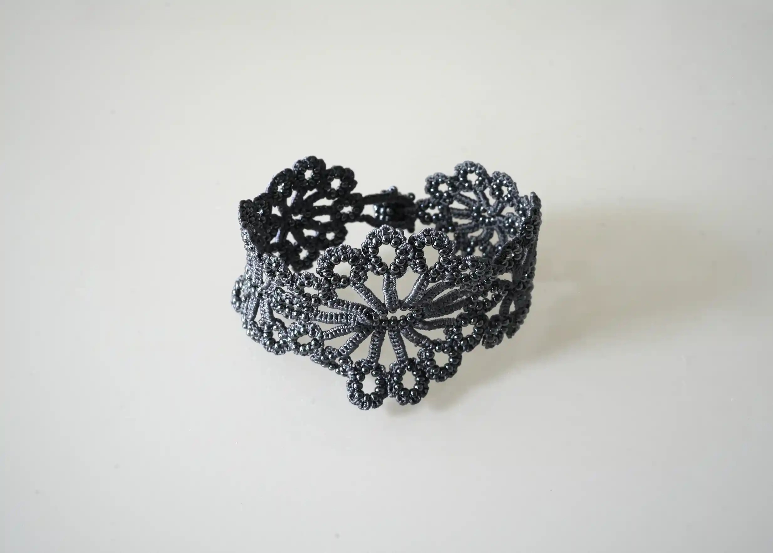 Handmade slate blue Hawa lace bracelet placed on a white background.