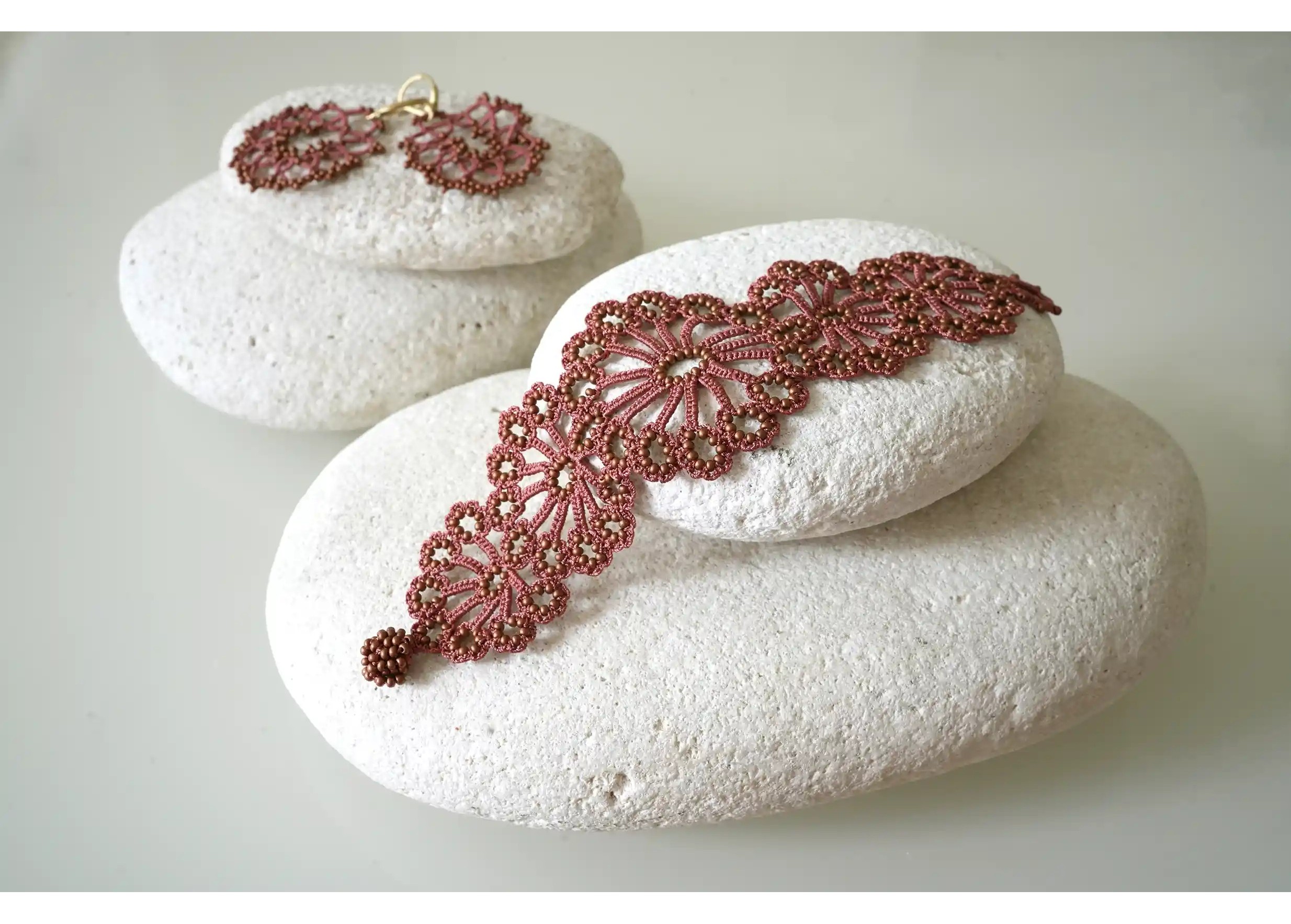 A Matt copper Hawa lace bracelet next to matching earrings