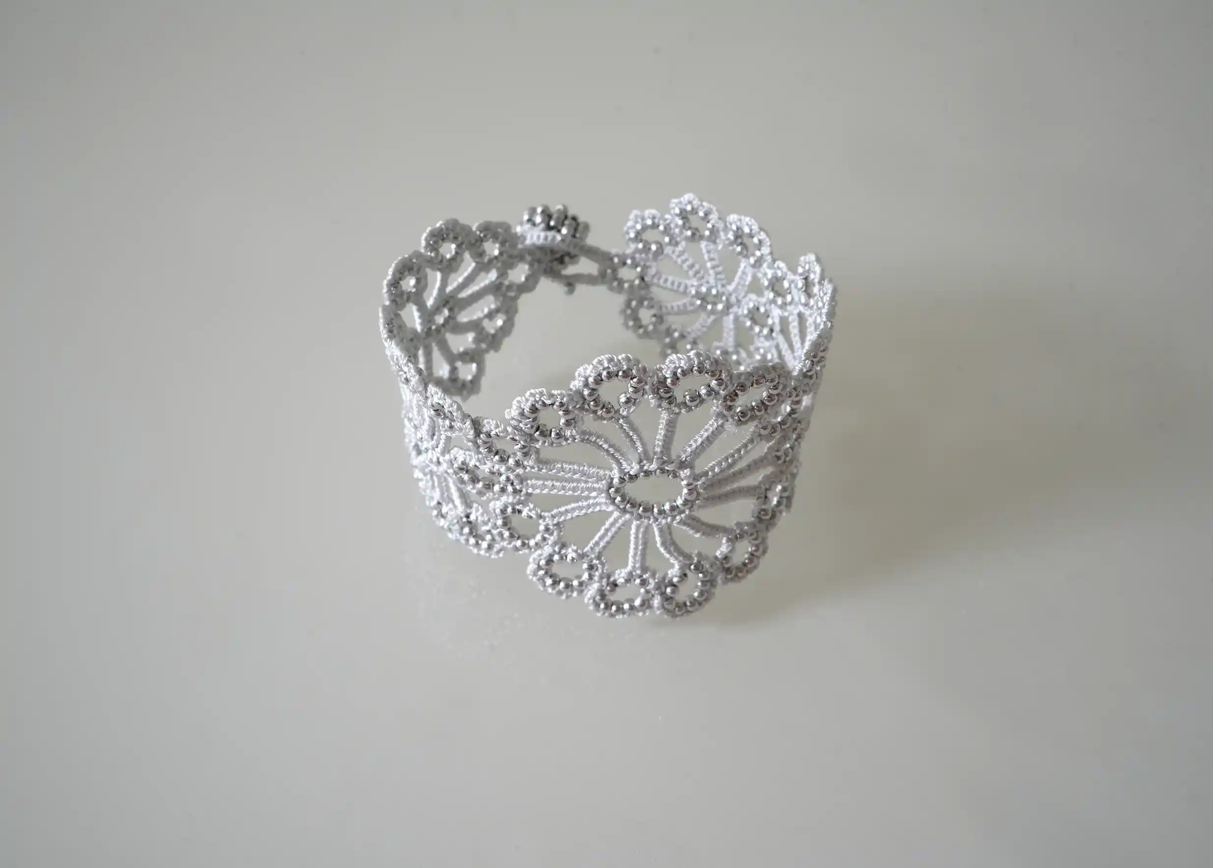 Bracelet Hawa coloris gris argent en dentelle fait main posé sur un fond blanc