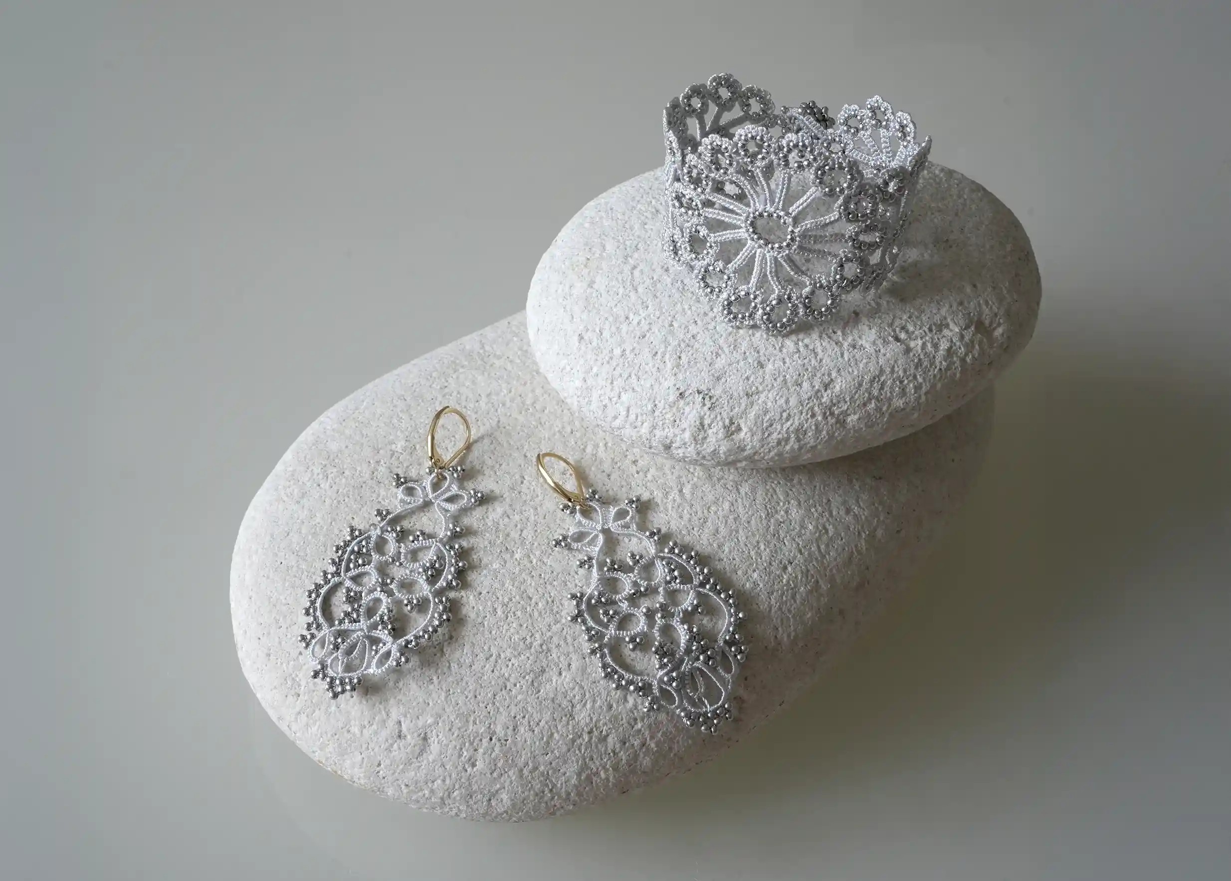 A silver grey Hawa lace bracelet next to matching earrings
