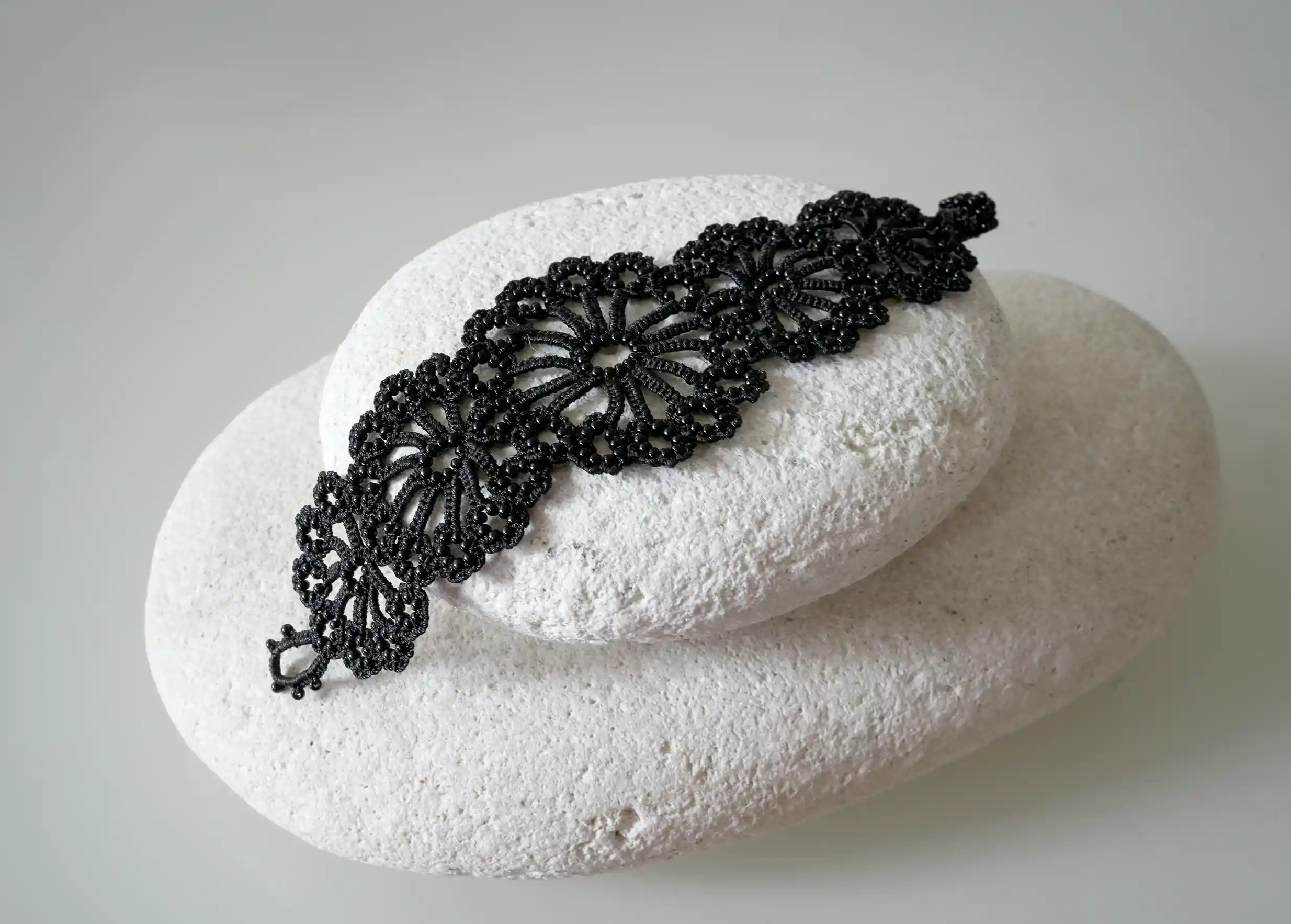 Vue des motifs du bracelet Hawa fait main en dentelle turque posé sur un galet