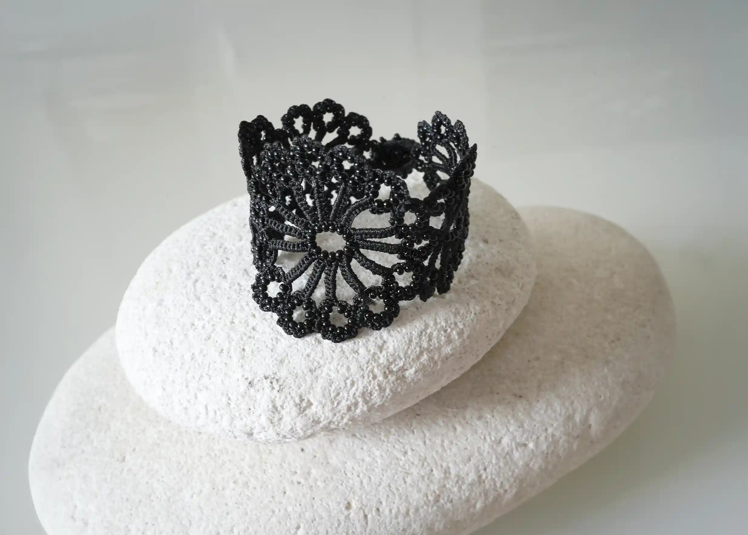 Hawa lace bracelet in matte gold, adorned with pearls, placed on a white pebble