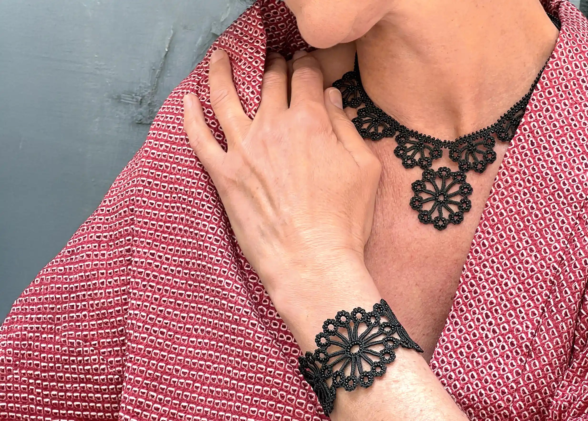 Woman in a red outfit wearing a black lace bracelet by Karawan