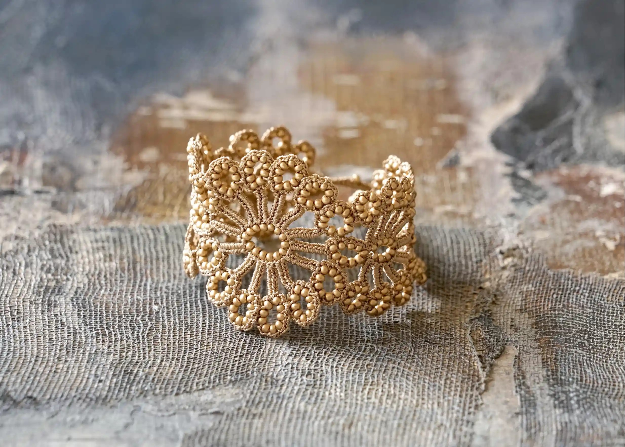 Hawa lace bracelet in beige gold, placed on a surface with a play of shadows
