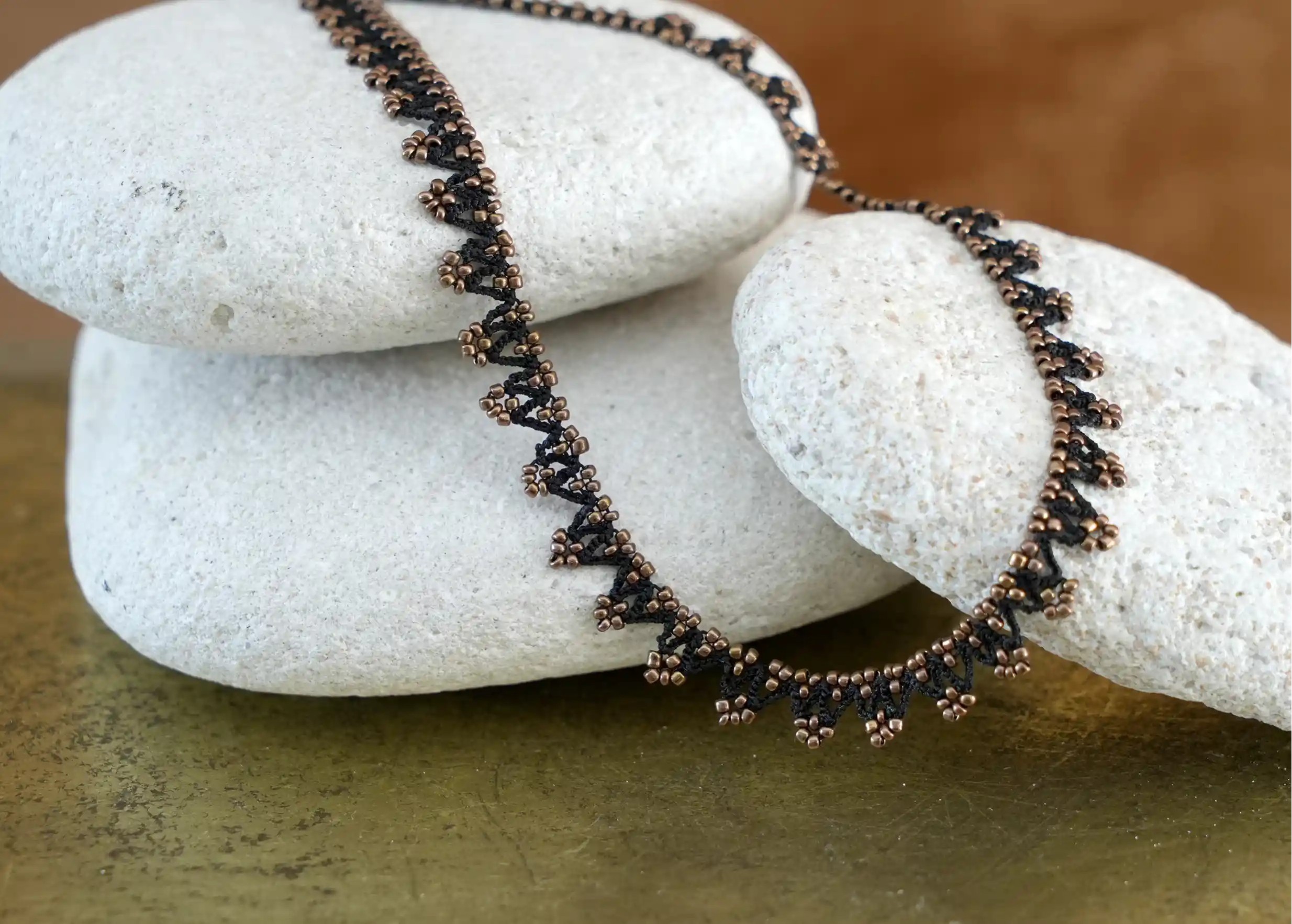 Zoom sur les details du collier 'Liana' en dentelle OYA, coloris noir et bronze