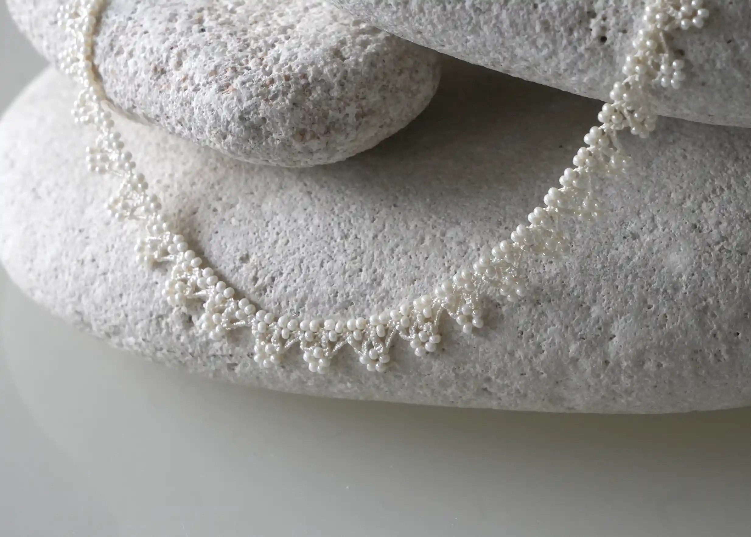 Zoom sur les détails du bijoux textile en dentelle coloris ivoire clair, marque Karawan authentic