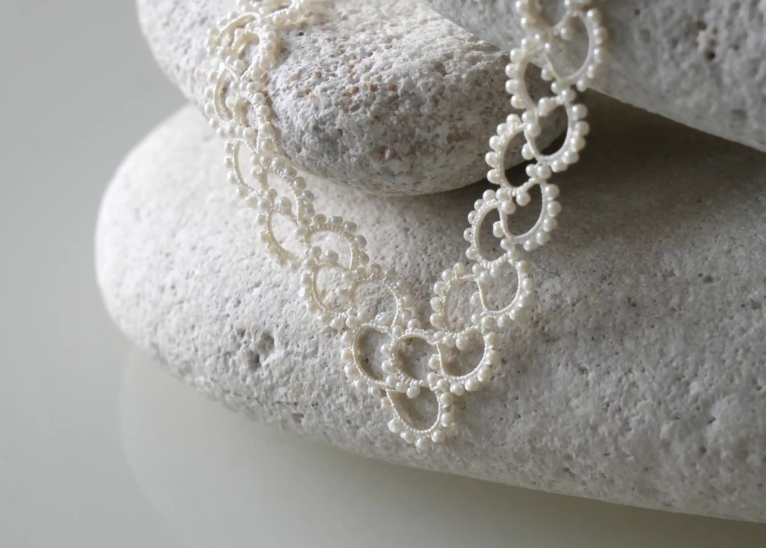 Zoom sur le collier en dentelle et perles réalisé à la main, modèle Seed et coloris ivoire clair