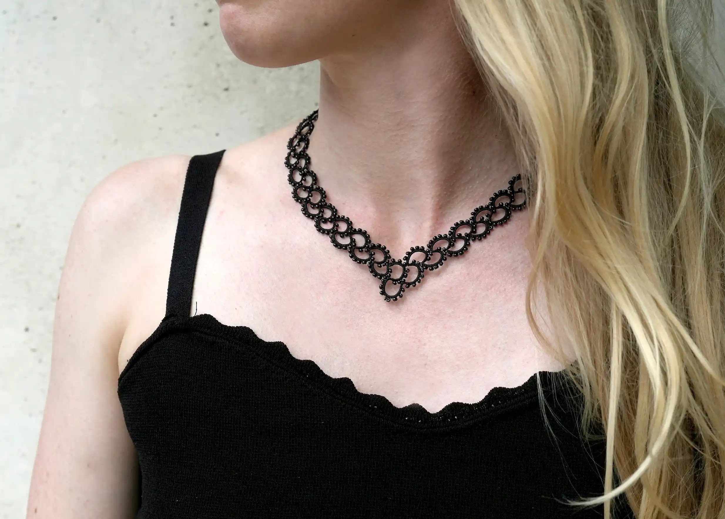 Femme portant un collier en dentelle et perles réalisé à la main, modèle Seed et coloris noir