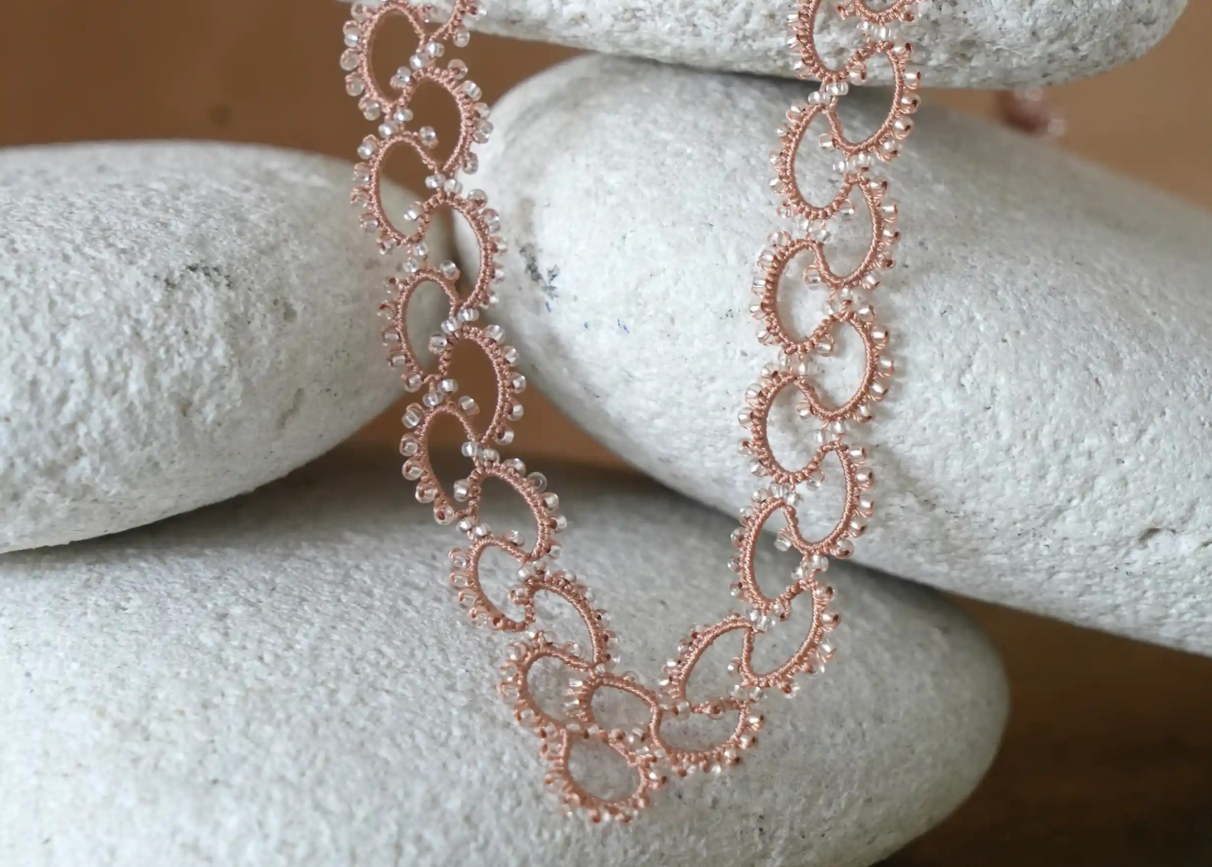 Zoom sur le collier en dentelle et perles réalisé à la main, modèle Seed et coloris terracotta et transparent