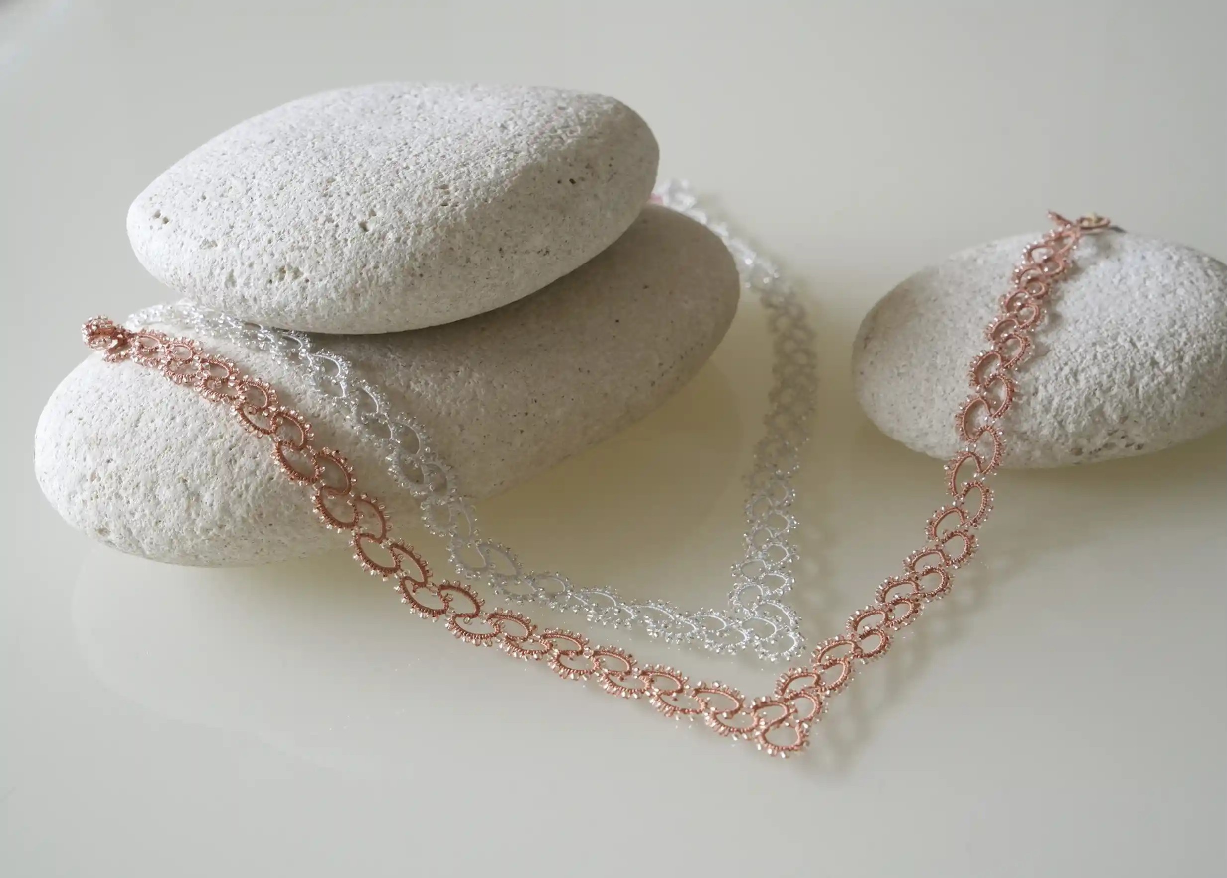 Duo de colliers en dentelle et perles réalisé à la main, modèle Seed, photo sur galet