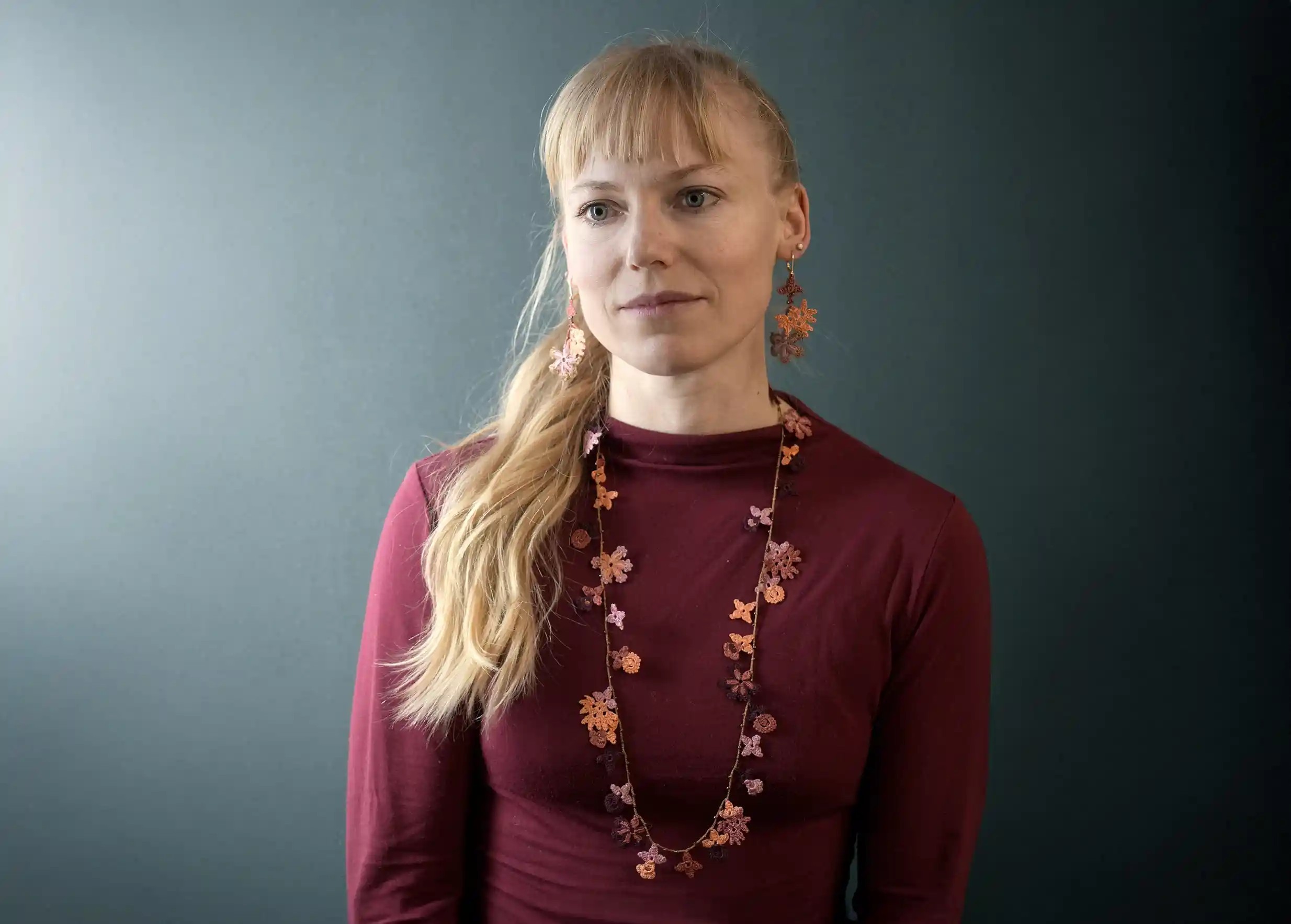 Woman wearing a lace necklace with floral and leaf motifs, Bloom in woody colour