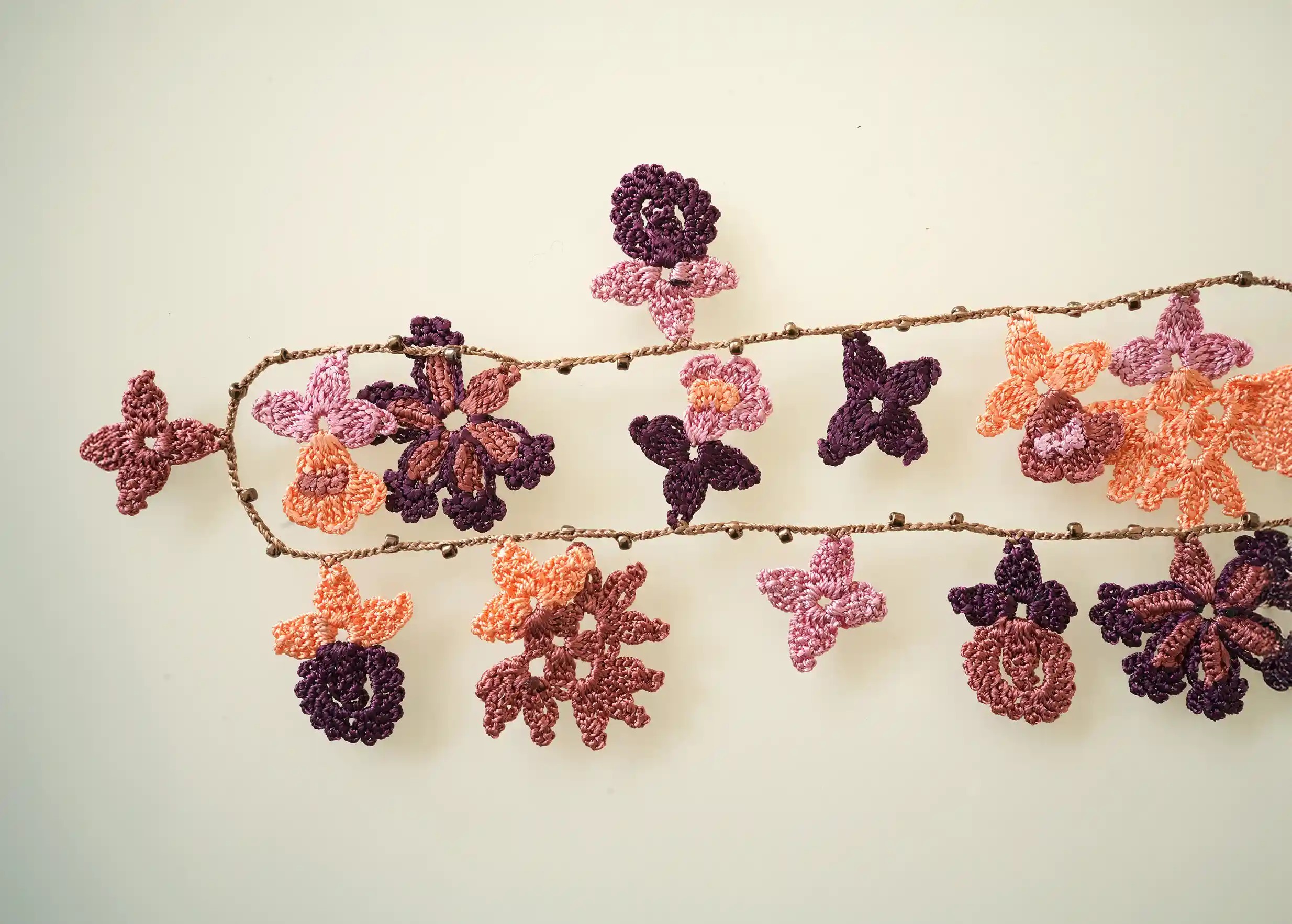 Focus on the lace necklace with floral and leaf motifs, Bloom in woody colour