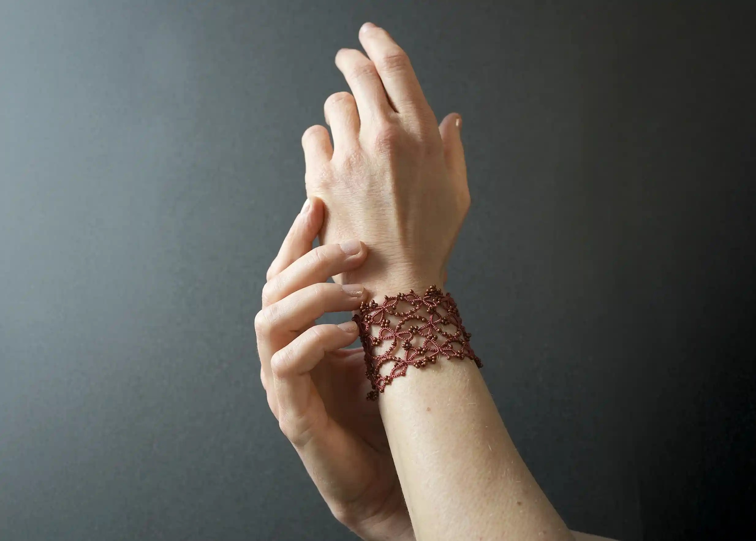 Bracelet manchette large en dentelle porté autour du poignet, modèle Crown coloris cuivre mat