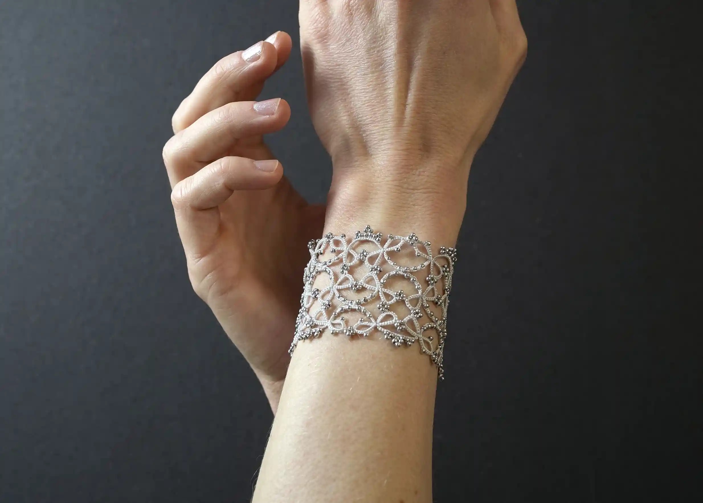 Focus on the wide lace cuff bracelet worn around the wrist, silver grey colour