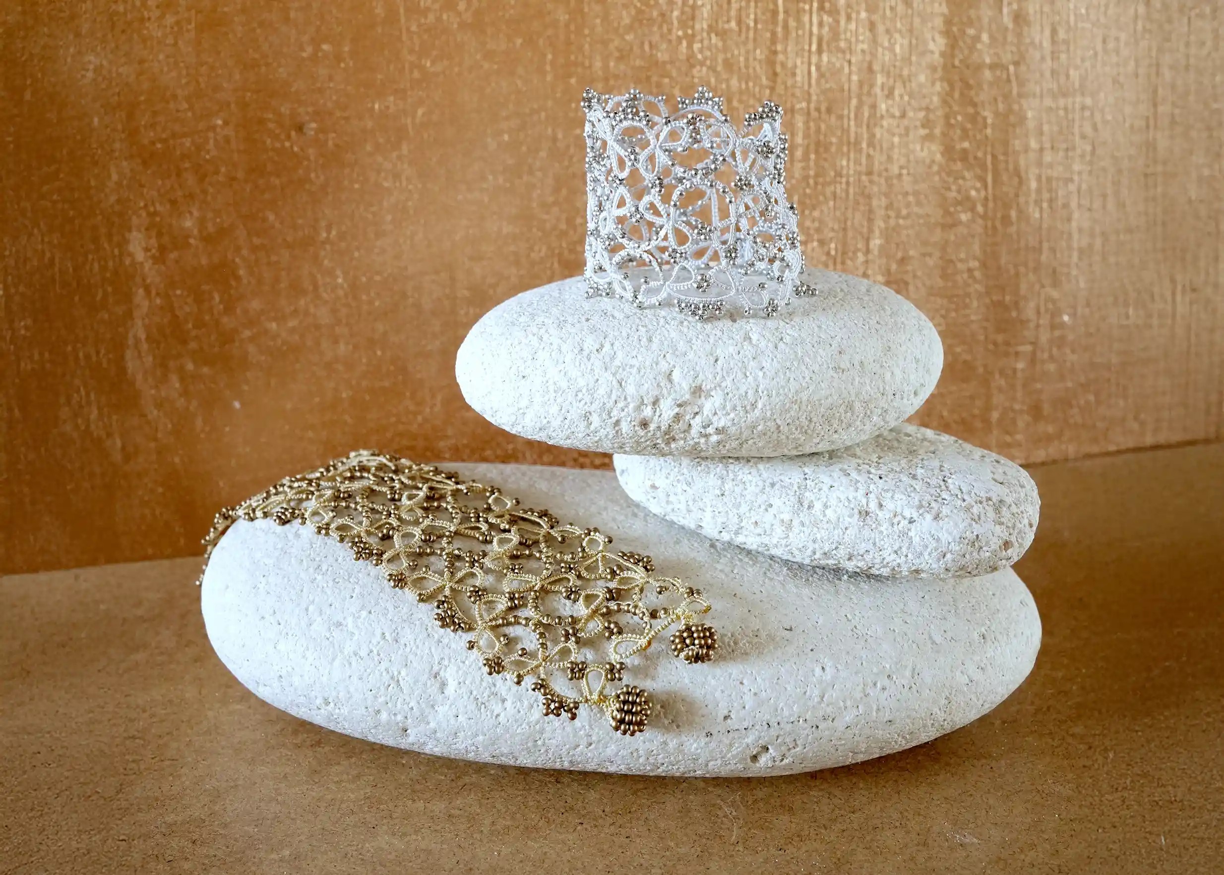 Bracelet manchette fait main en dentelle de Karawan délicatement posé sur un galet, modèle Crown