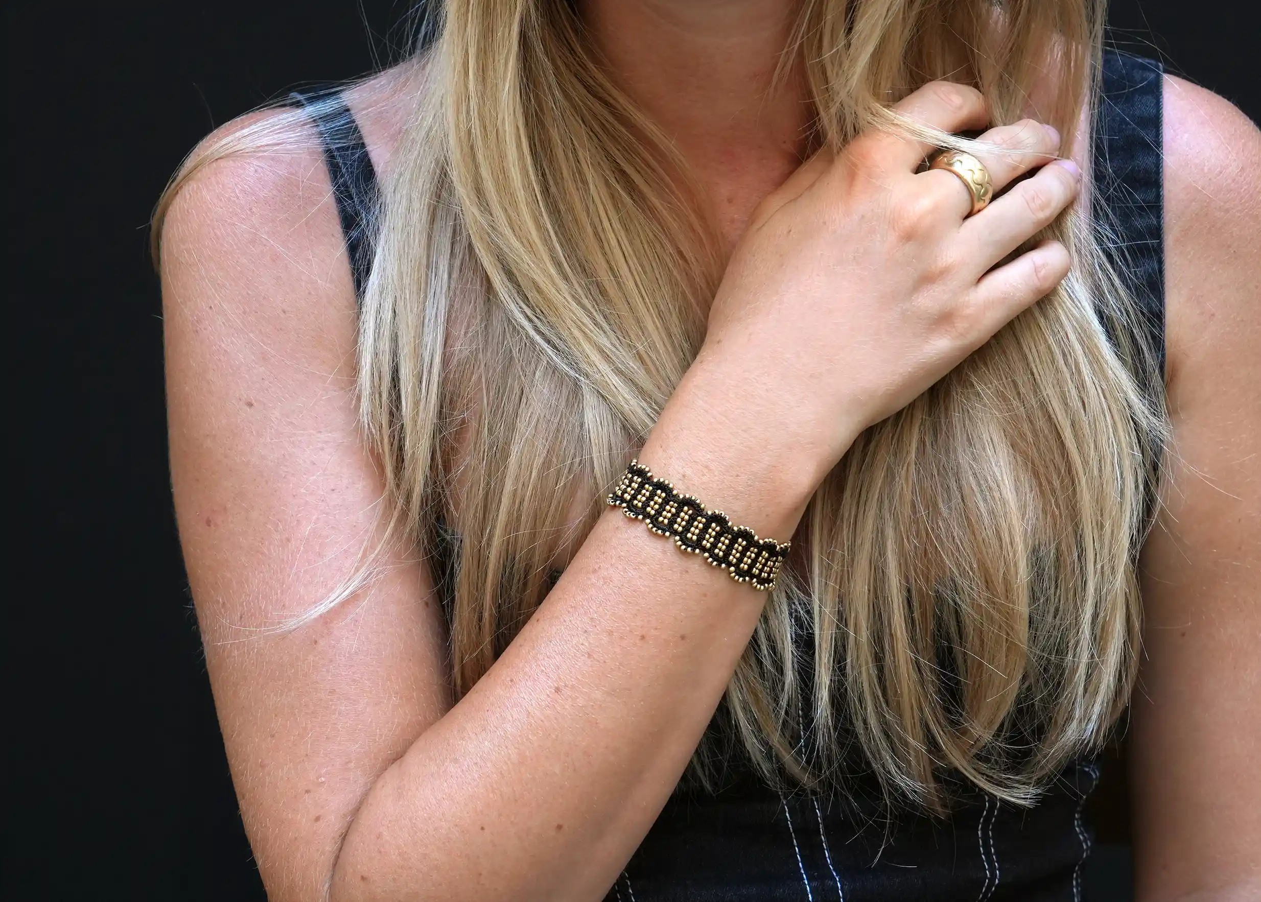 Young woman wearing a black and matt gold thread and bead bracelet, hand-crocheted, Bark model