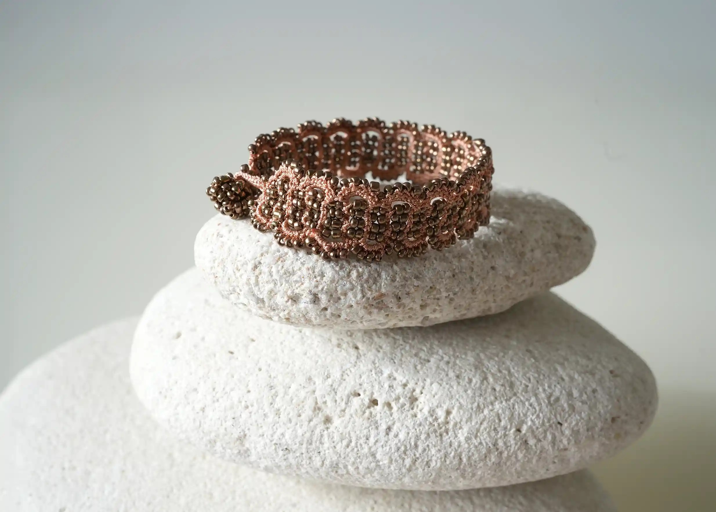Terracotta copper-coloured thread and bead bracelet set on a pebble, Bark model