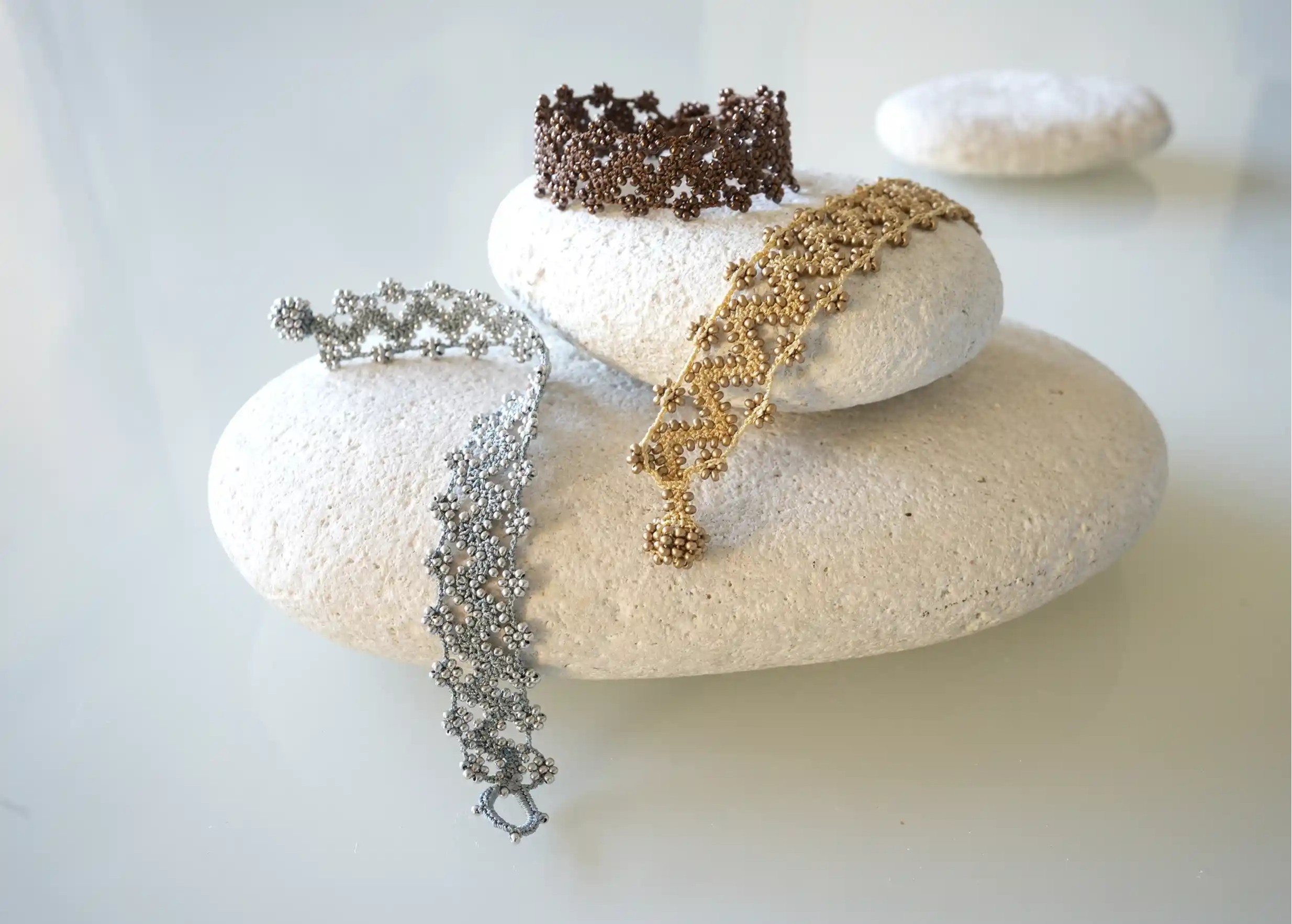 Set of three textile bracelets made from thread and beads, with graphic patterns, Ribbon model