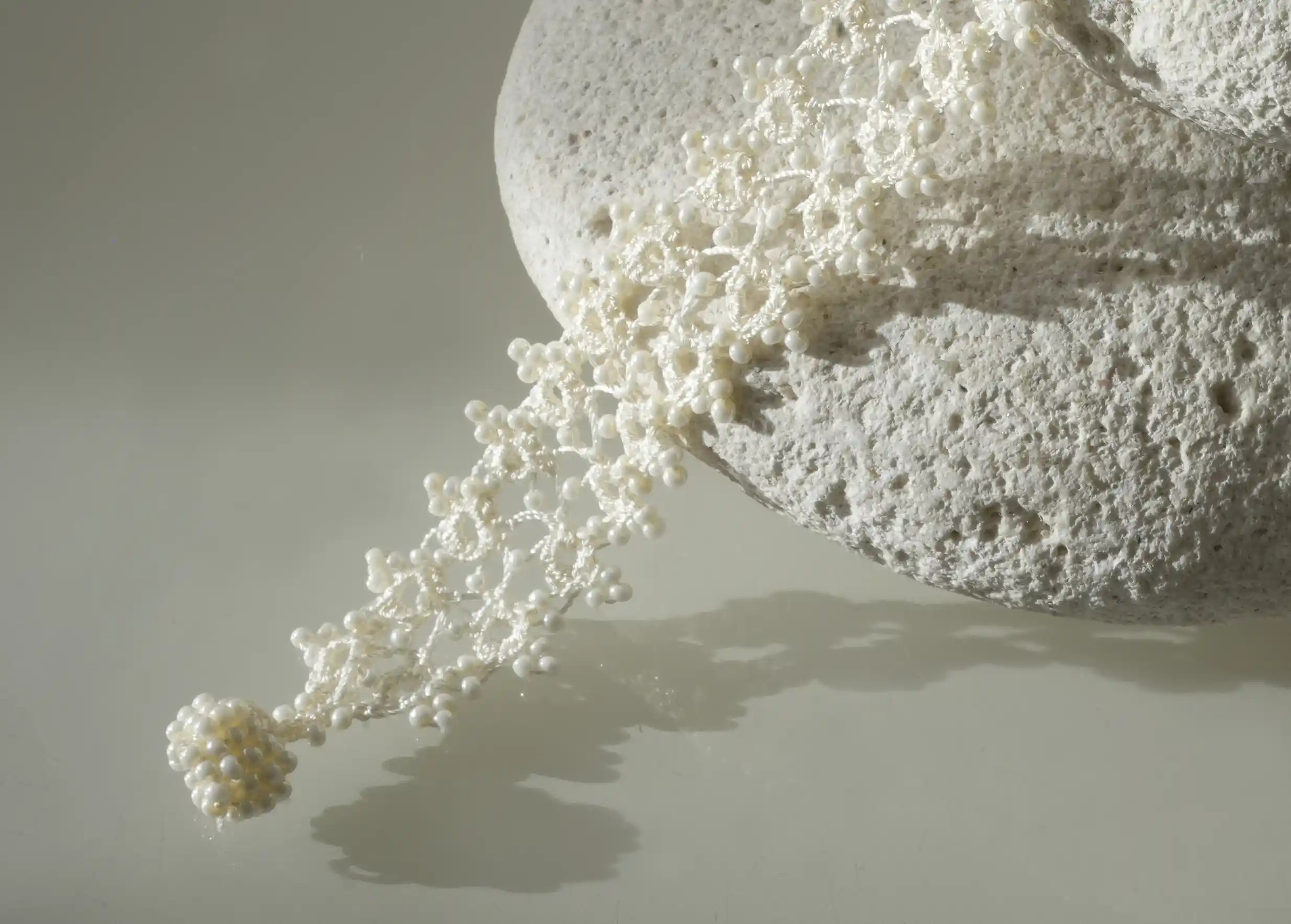 Bracelet textile en dentelle fait main,  Husnu, collection OYA, coloris bleu ivoire clair sur un galet