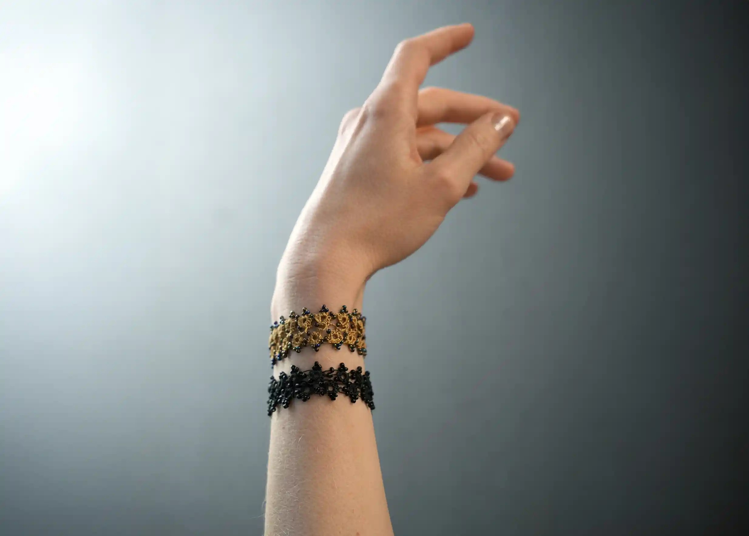 Duo de bracelets textiles en dentelle fait main, portés autour d'un poignet féminin