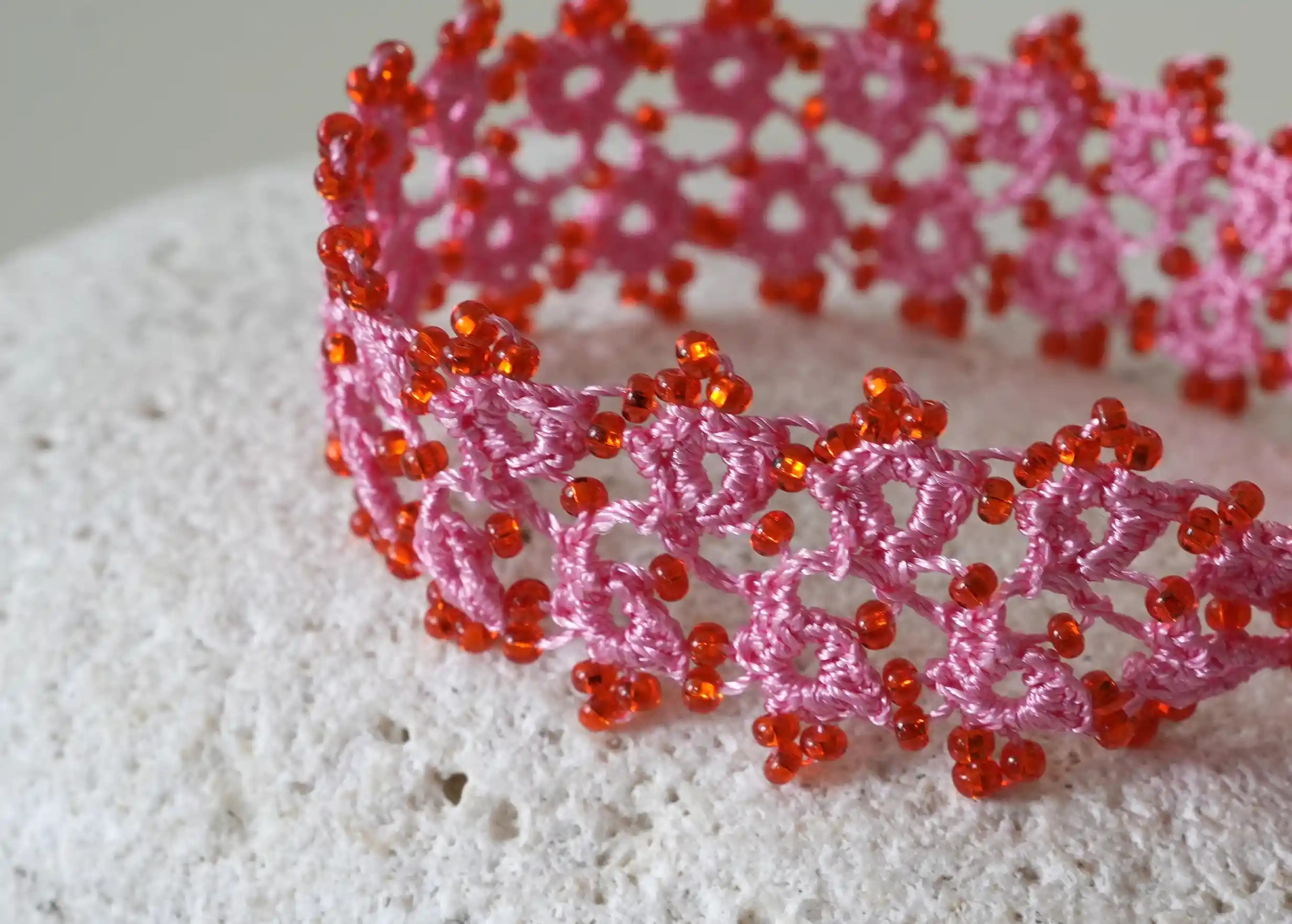Focus on the handmade lace textile bracelet, Husnu, OYA collection, pink and red colours
