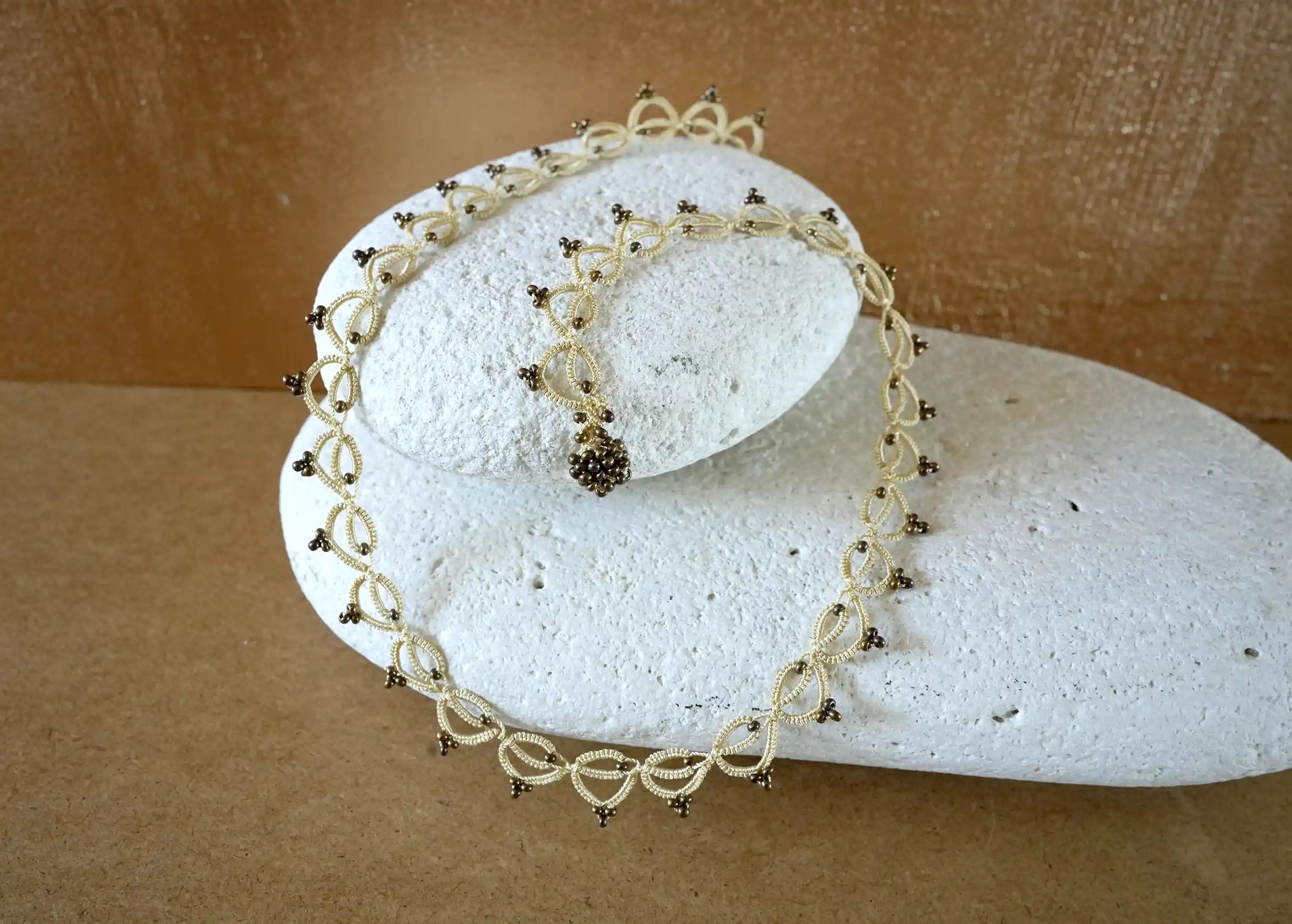 Collier tour de cou fait main en fil et perles, Lotus Chain, photo prise sur un galet