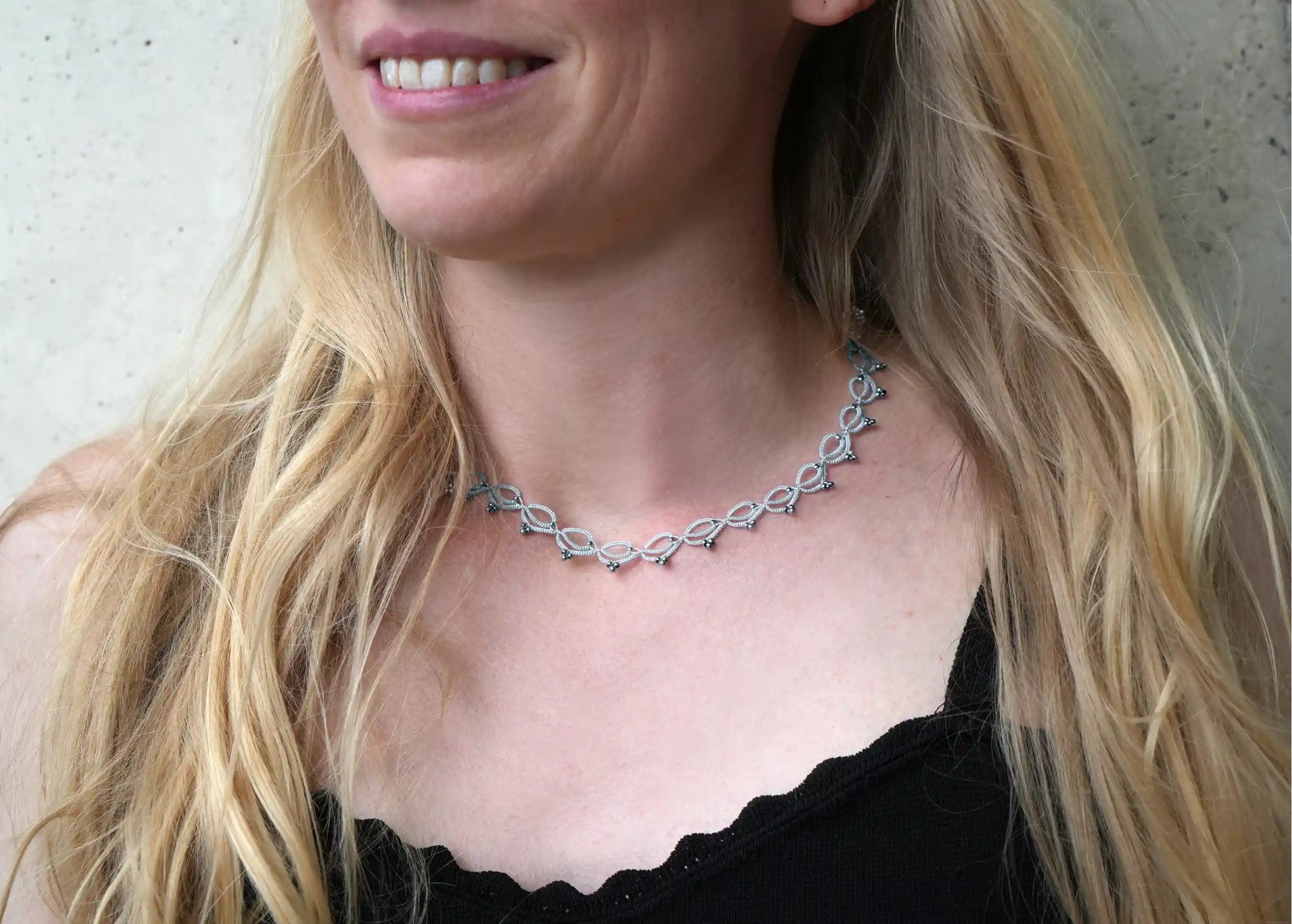 Woman wearing a handmade choker necklace made of thread and pearls, Lotus Chain in glacier blue and silver