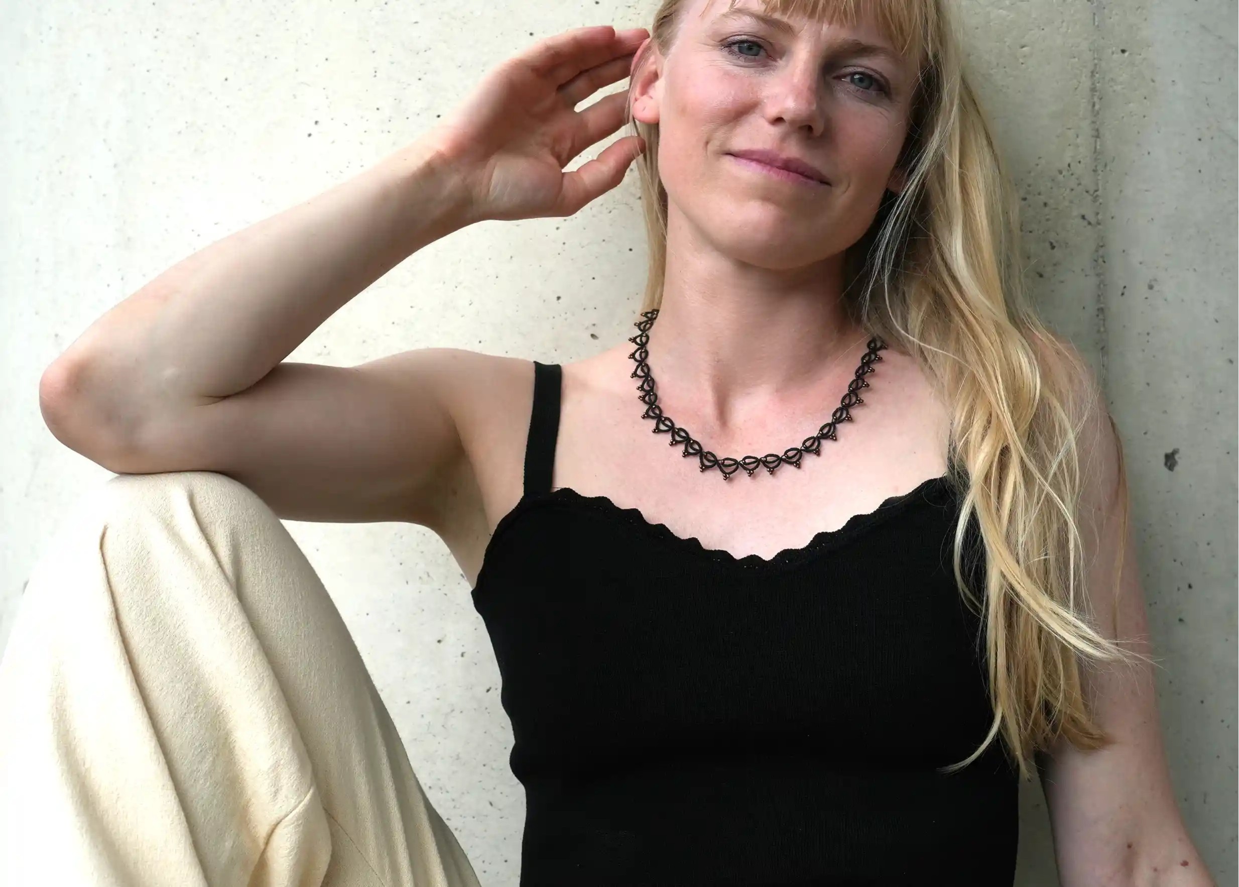 Smiling woman wearing a handmade choker necklace made of thread and beads, Lotus Chain in black