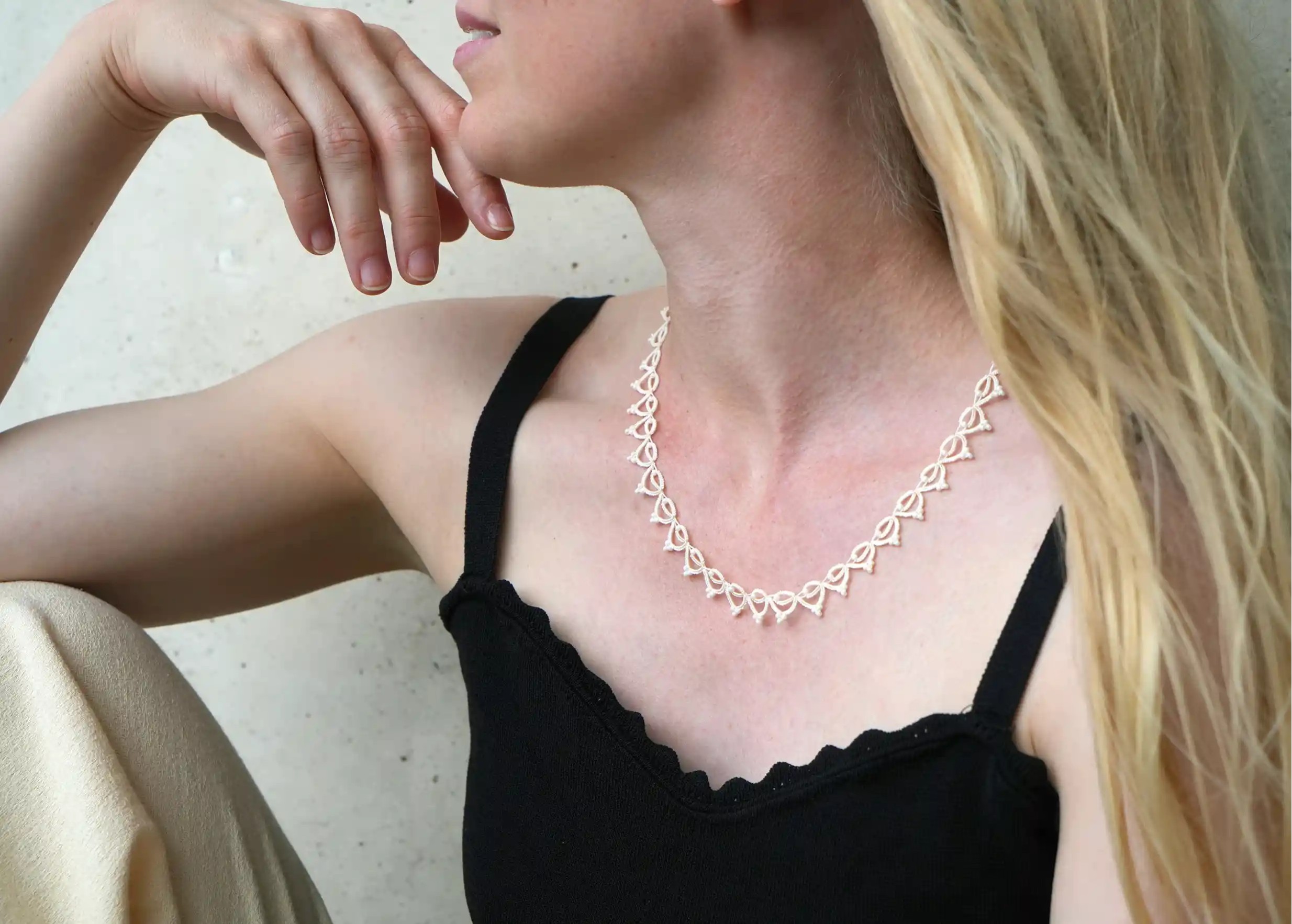 Femme portant le collier tour de cou fait main en fil et perles, Lotus Chain coloris ivoire clair