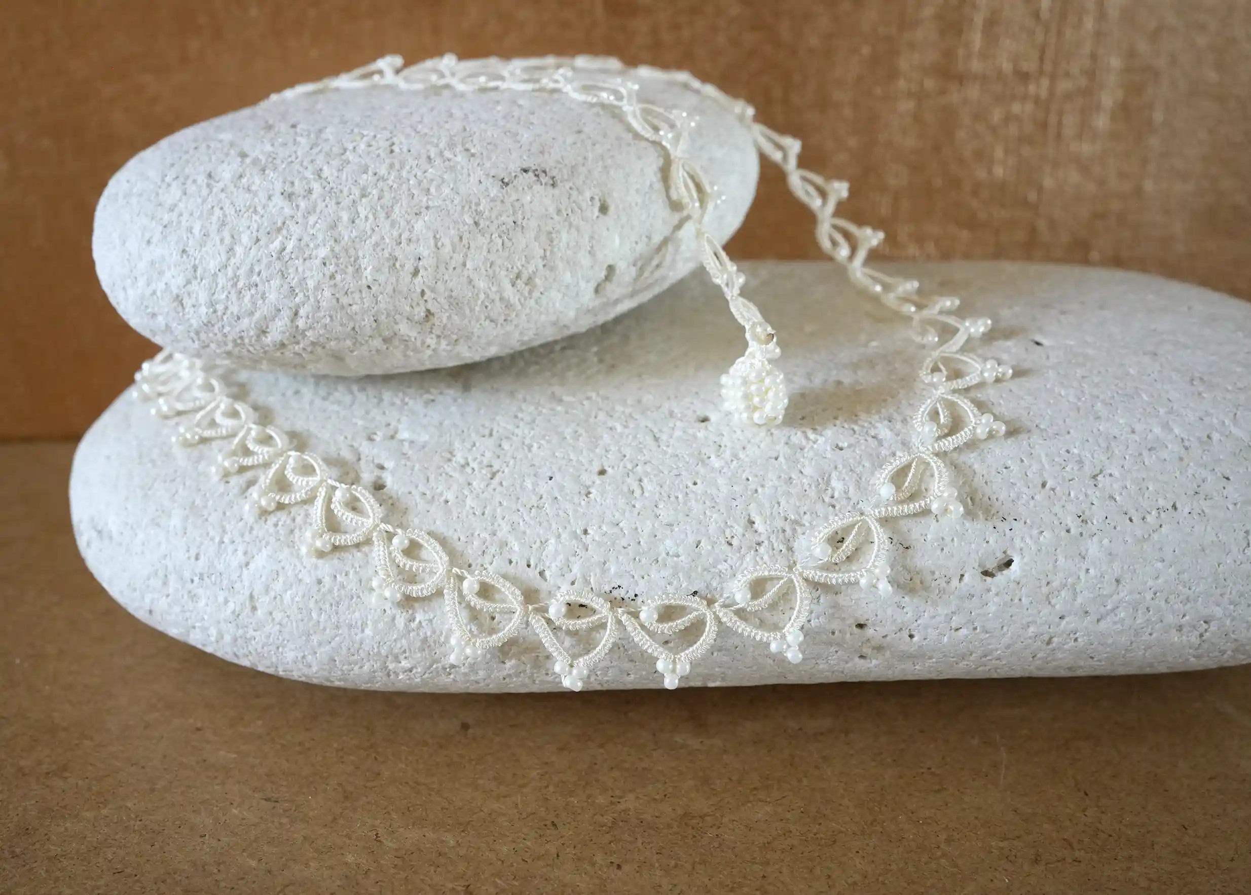 Focus on the handmade choker necklace made of thread and pearls, Lotus Chain in light ivory colour