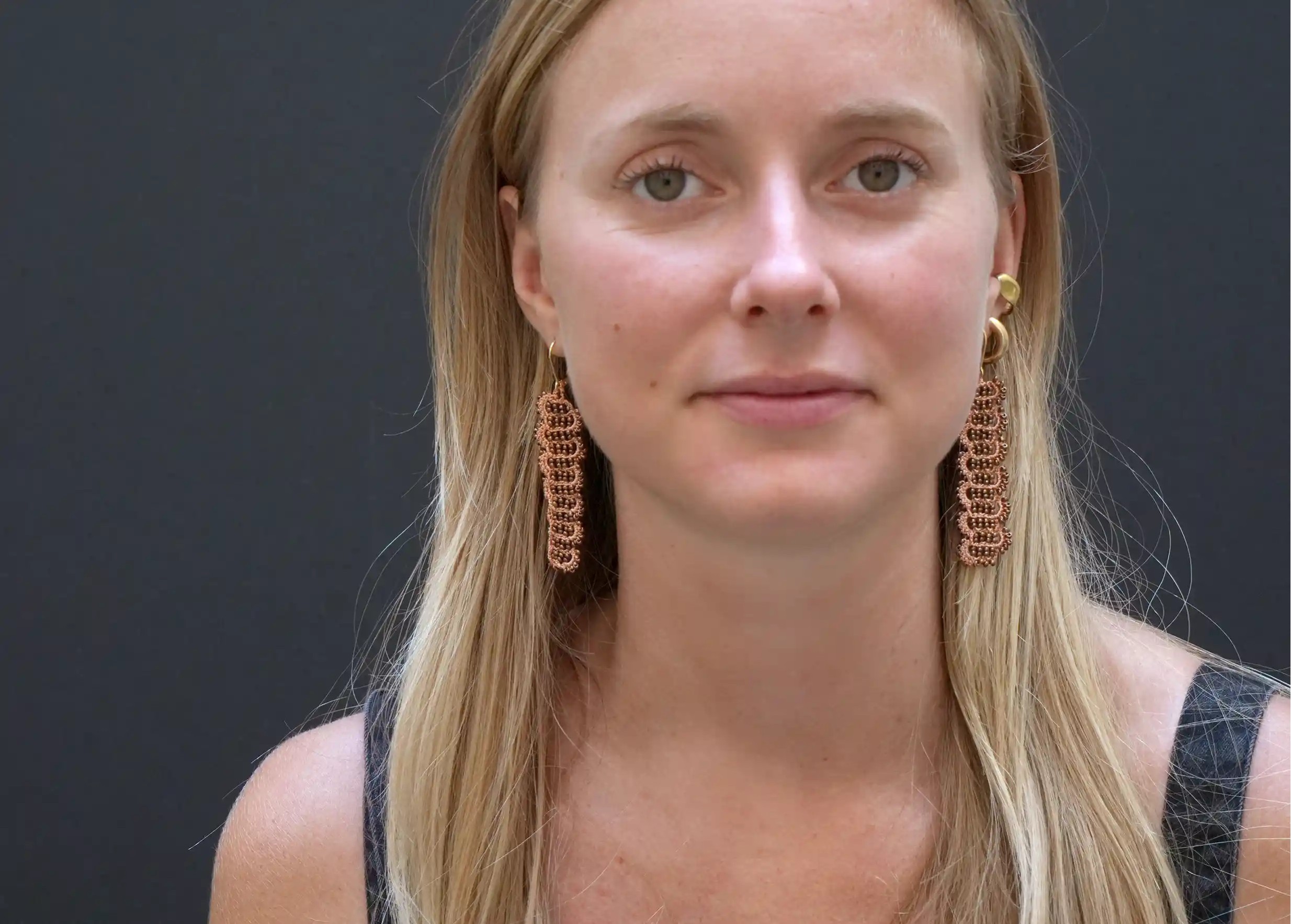 Femme portant des boucles d'oreilles en fil et perles métalliques, modèle Bark, coloris Terracotta et cuivre