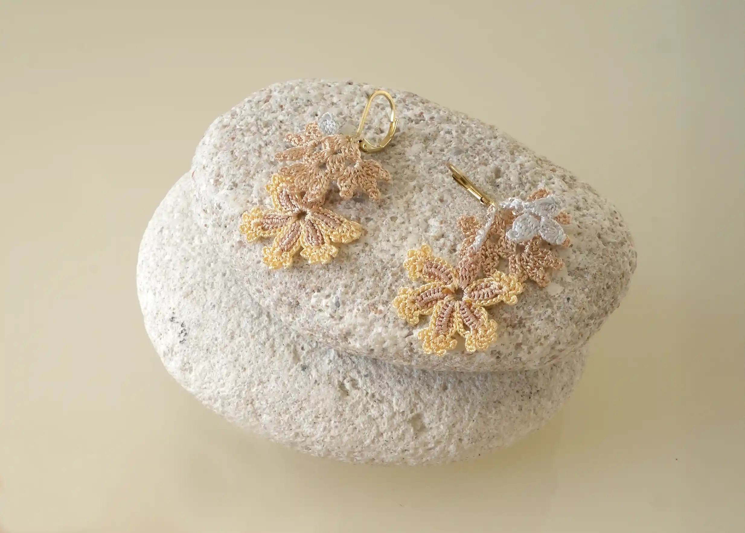 Boucles d'oreilles en dentelle de fil et de perles, coloris nacre, photo prise sur galets