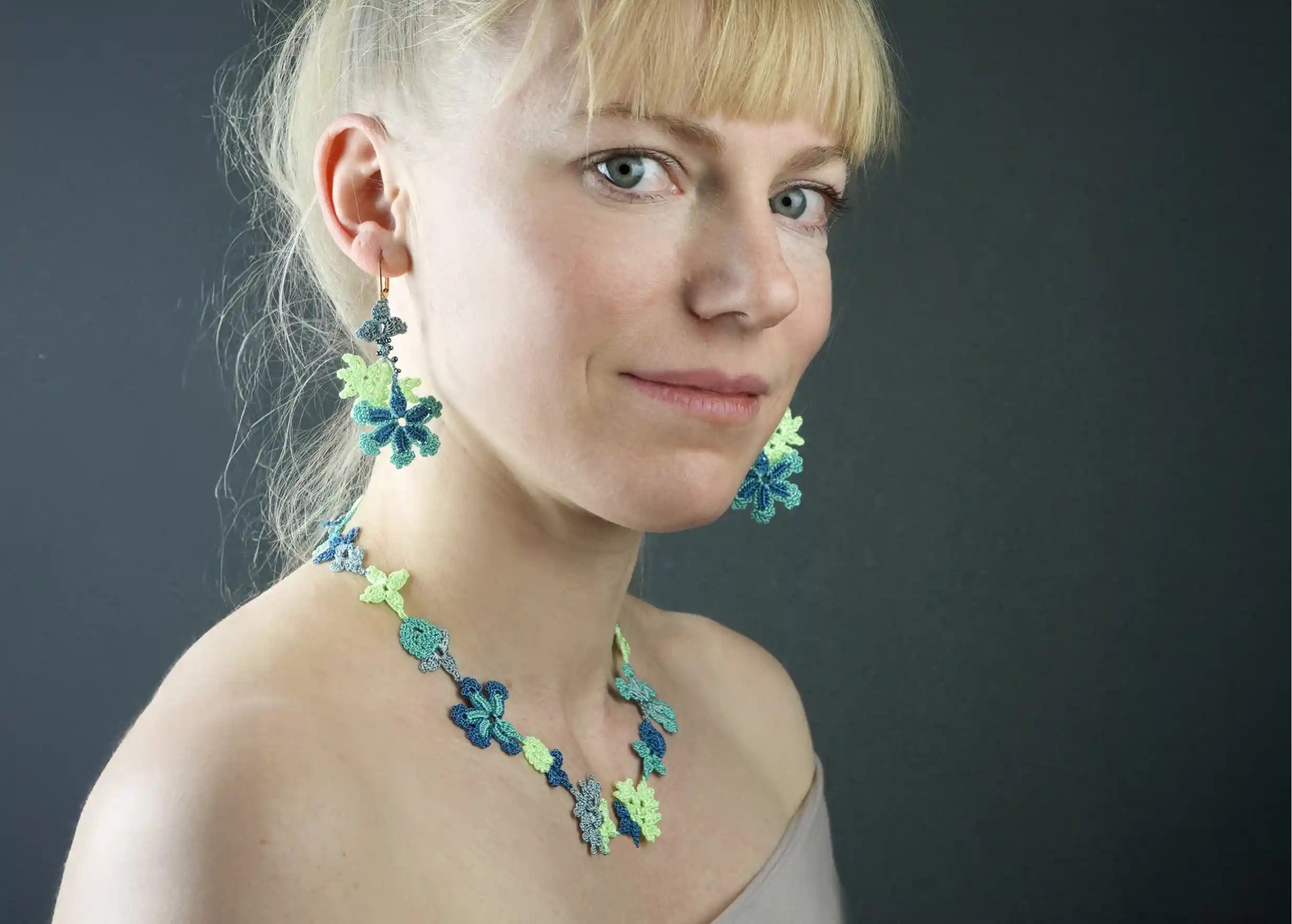 Woman wearing Bloom lace thread and pearl earrings, ocean colour