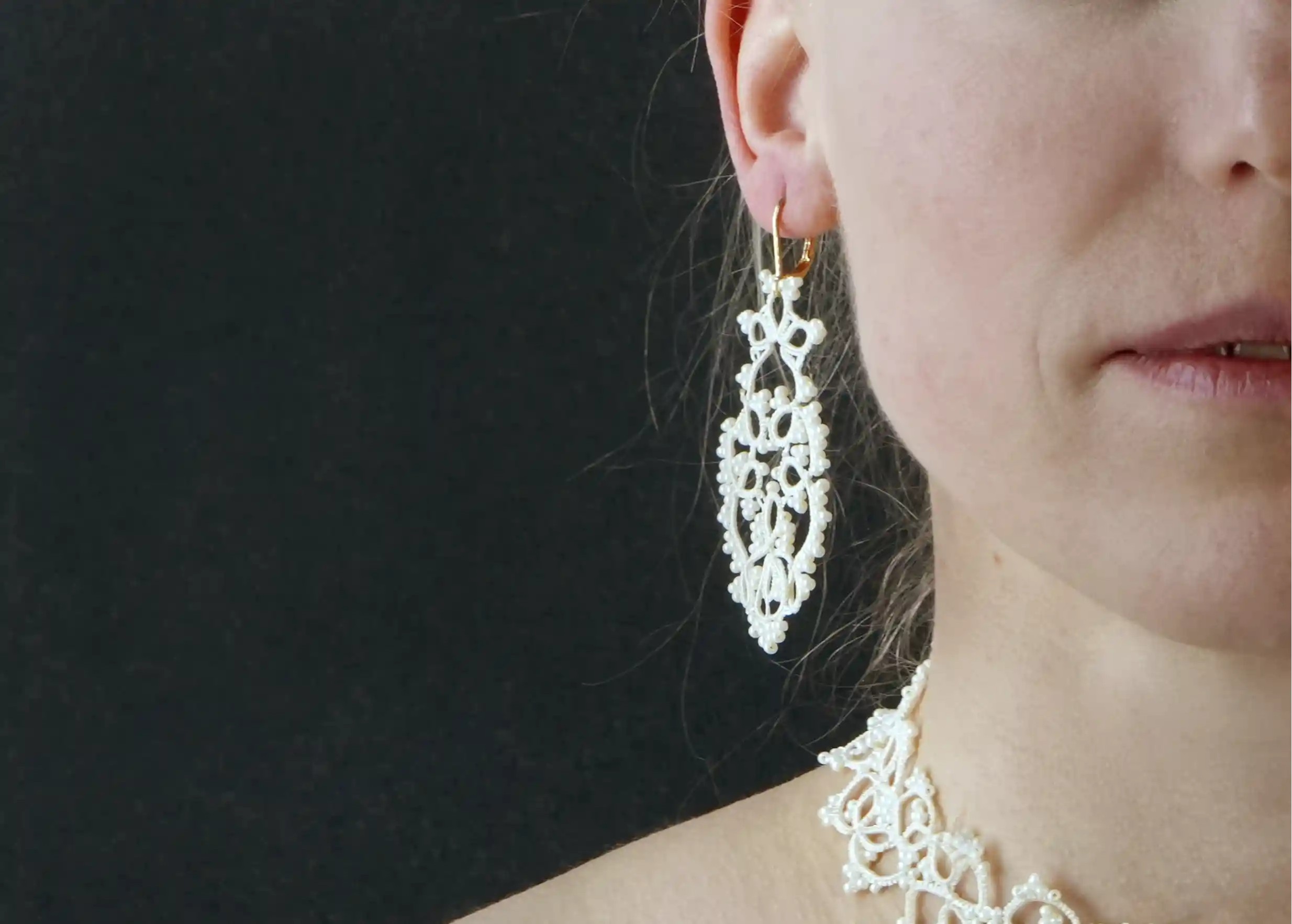 Close-up of the details of the handmade lace earrings, TREE model, light ivory colour