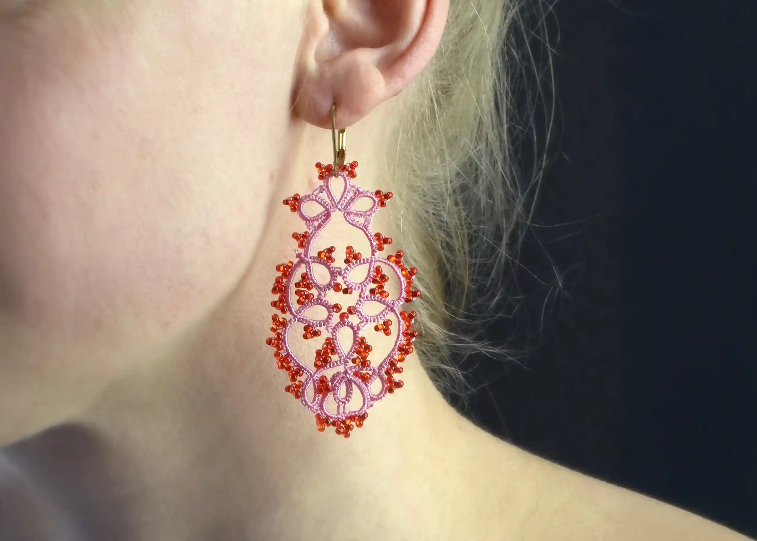 Close-up of the details of the handmade lace earrings, TREE model, rose red colour