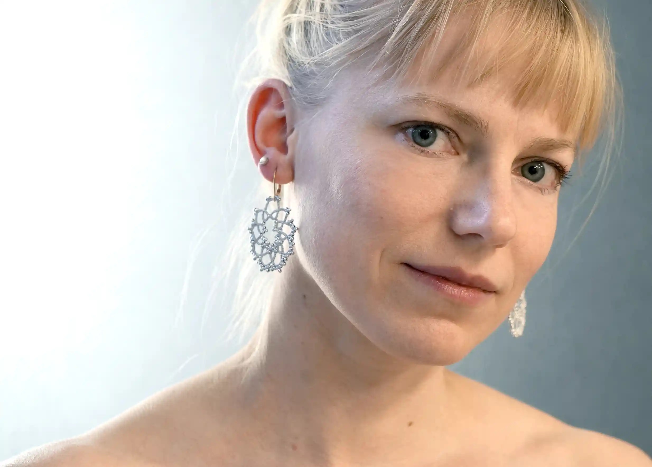 Femme portant des boucles d'oreilles réalisées en fil et perles, au motif géométrique, modèle Flower