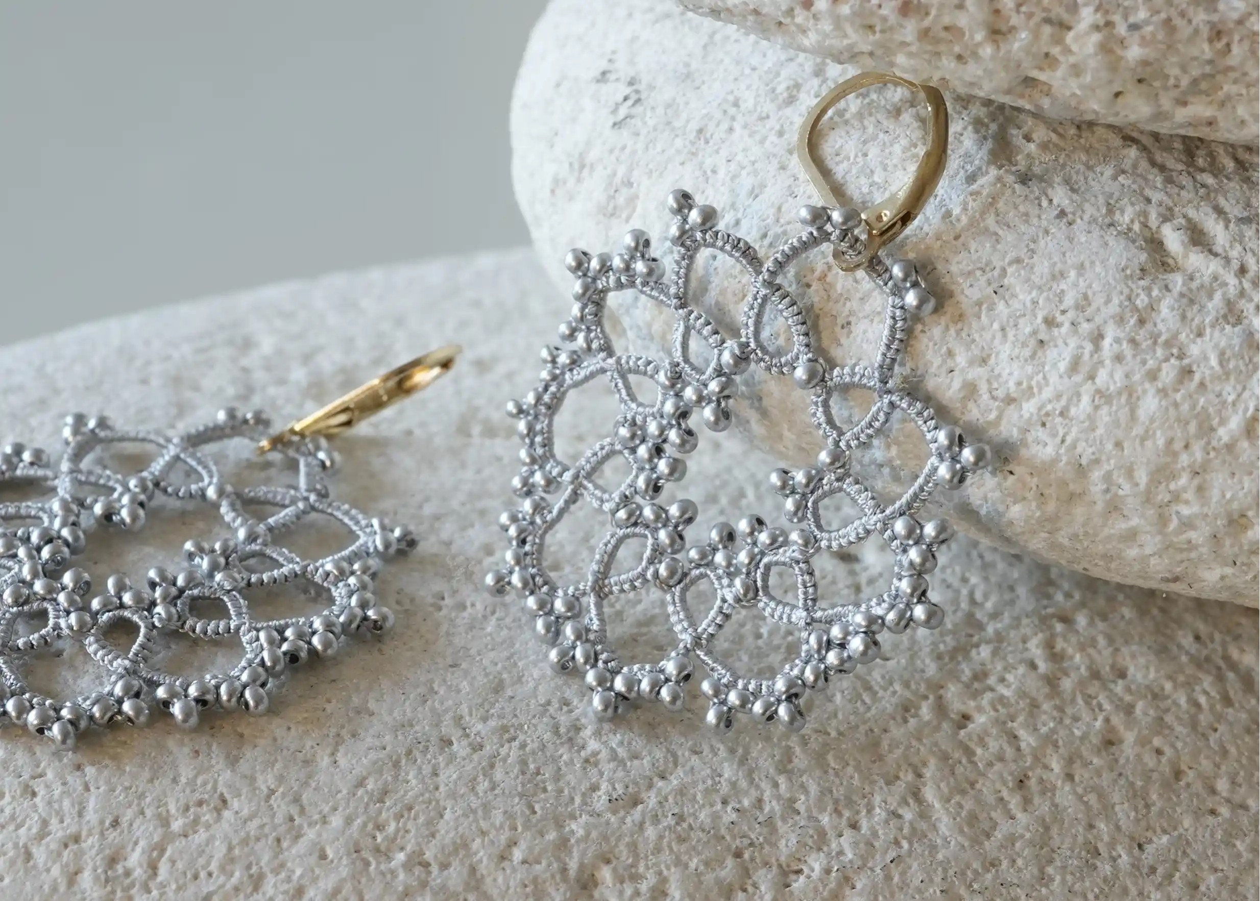 Zoom sur les details des boucles d'oreilles réalisées en fil et perles, au motif géométrique, modèle Flower