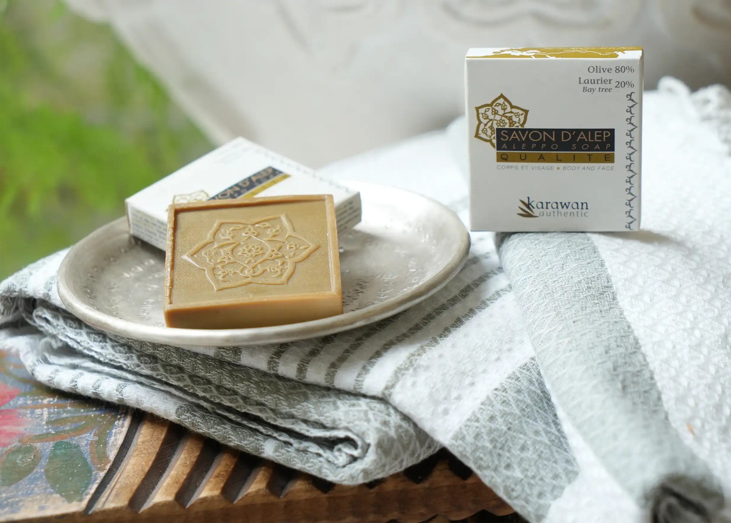 Mini Aleppo soap with 20% laurel oil on a brass dish, and a box of soap