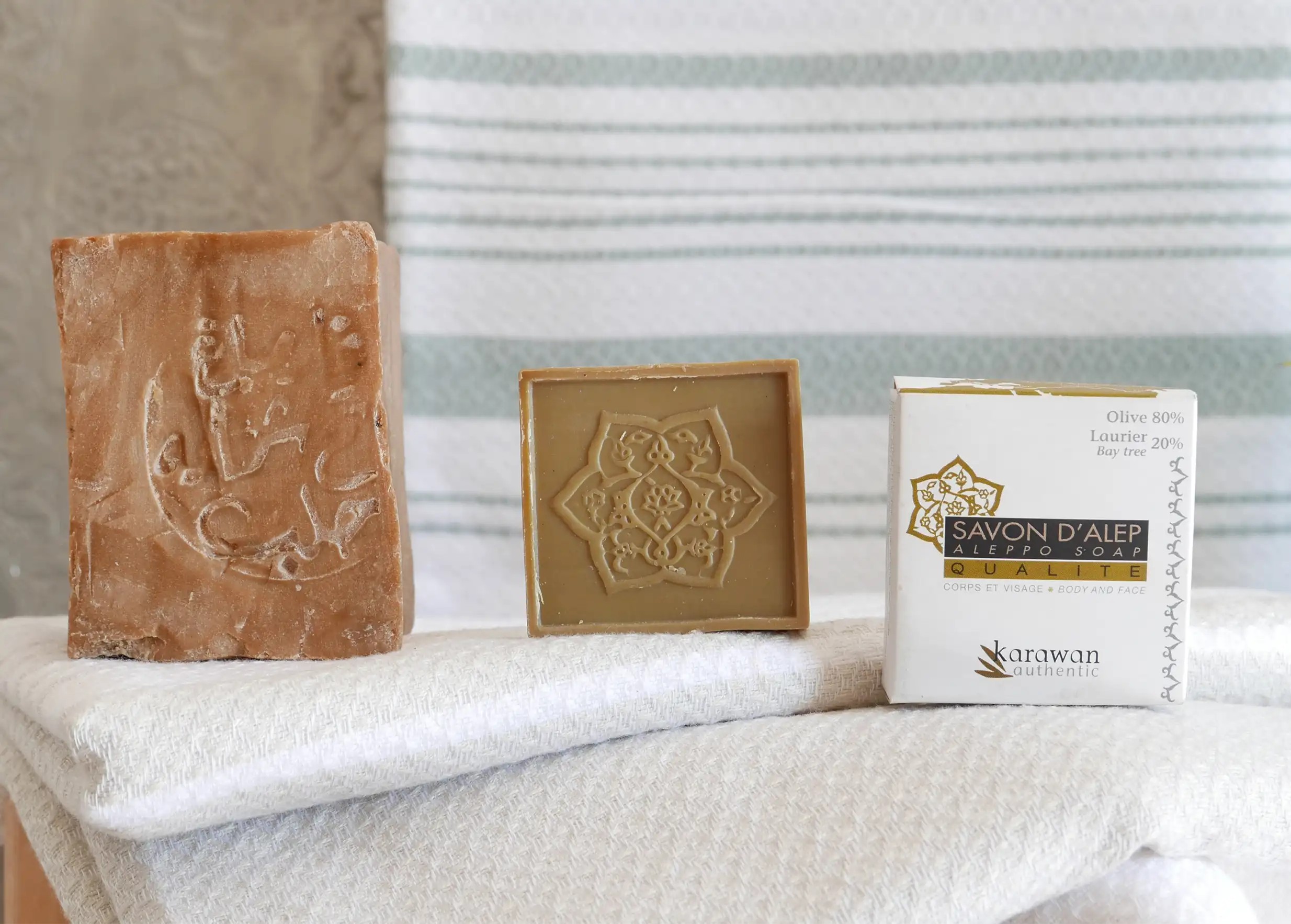 Trois savons d'Alep disposés sur une fouta à rayures