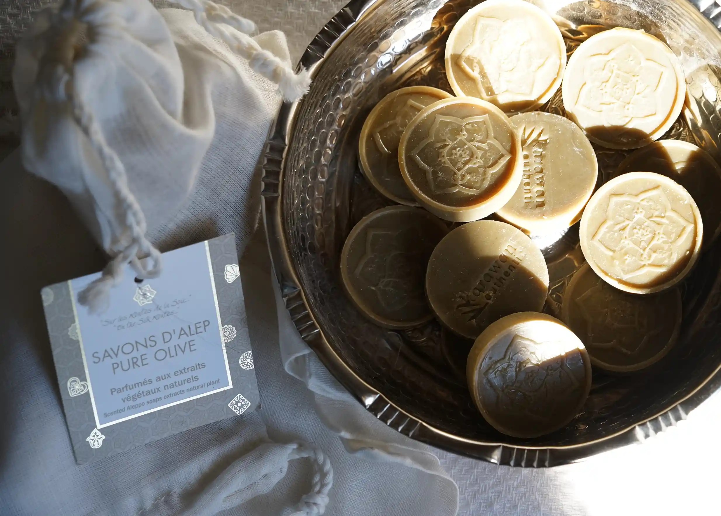 Savons d'Alep d'invités pure olive disposés dans un récipient, et accompagnés d'un pochon en tissu fin