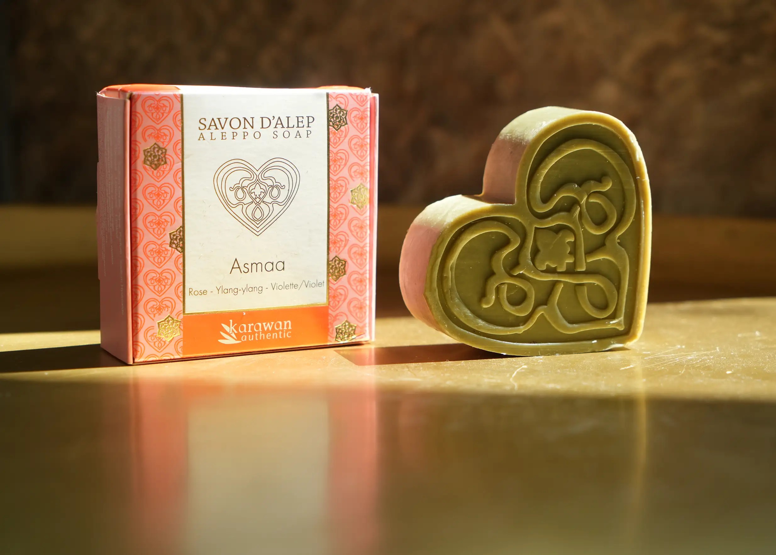 Savon d'Alep parfumé Asmaa, en forme de coeur et à la senteur de rose, à côté de son écrin doré