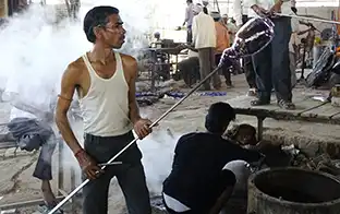 Artisan verrier manipulant une masse de verre en fusion