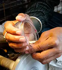 Mains d'artisan verrier manipulant un bol en verre