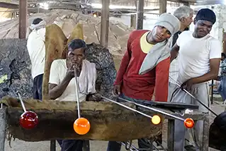 Artisans soufflant le verre pour y créer des formes