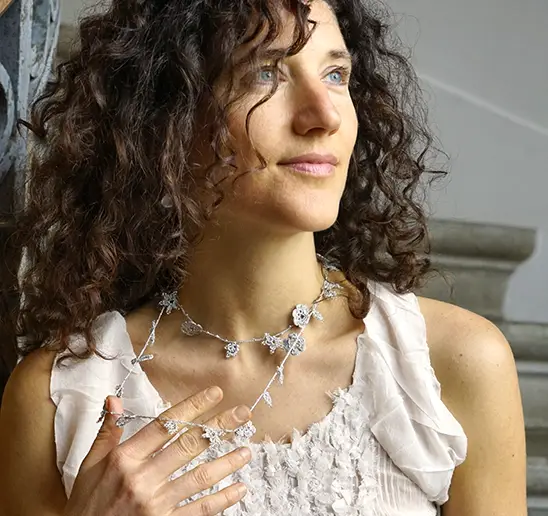 Sautoir en dentelle gris Crystal porté par une femme et légèrement tenu à la main