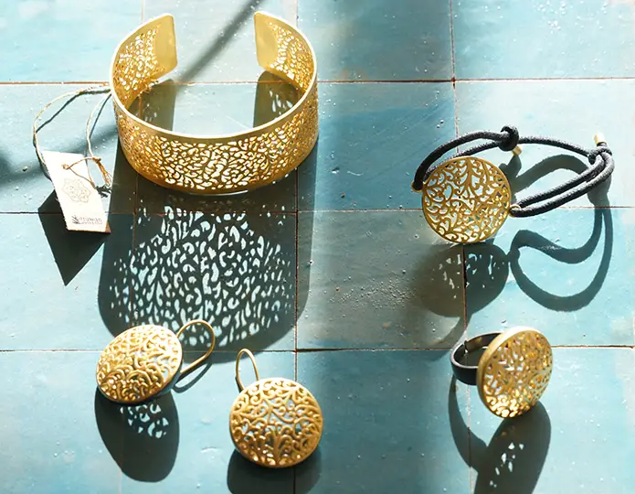Photo prise de haut de l'ensemble de bijoux en laiton de la gamme Jardin secret : manchette, bague, bracelet