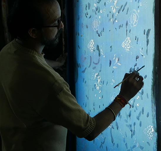 Un artiste à l’œuvre sur un tableau lumineux, symbole d’un savoir-faire authentique et d’une mode inspirée par l’art